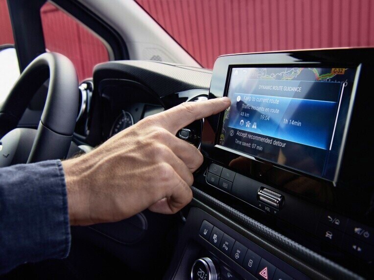 Chauffør i eCitan Kassevogn med fingeren på MBUX touchscreen