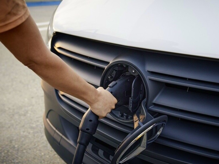 Person i færd med at oplade en Mercedes-Benz varebil via stik i kølergitteret