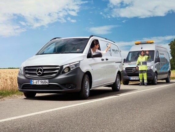Kvinde i hvid eVito vinker farvel til Mercedes-Benz mekaniker efter service på vejen
