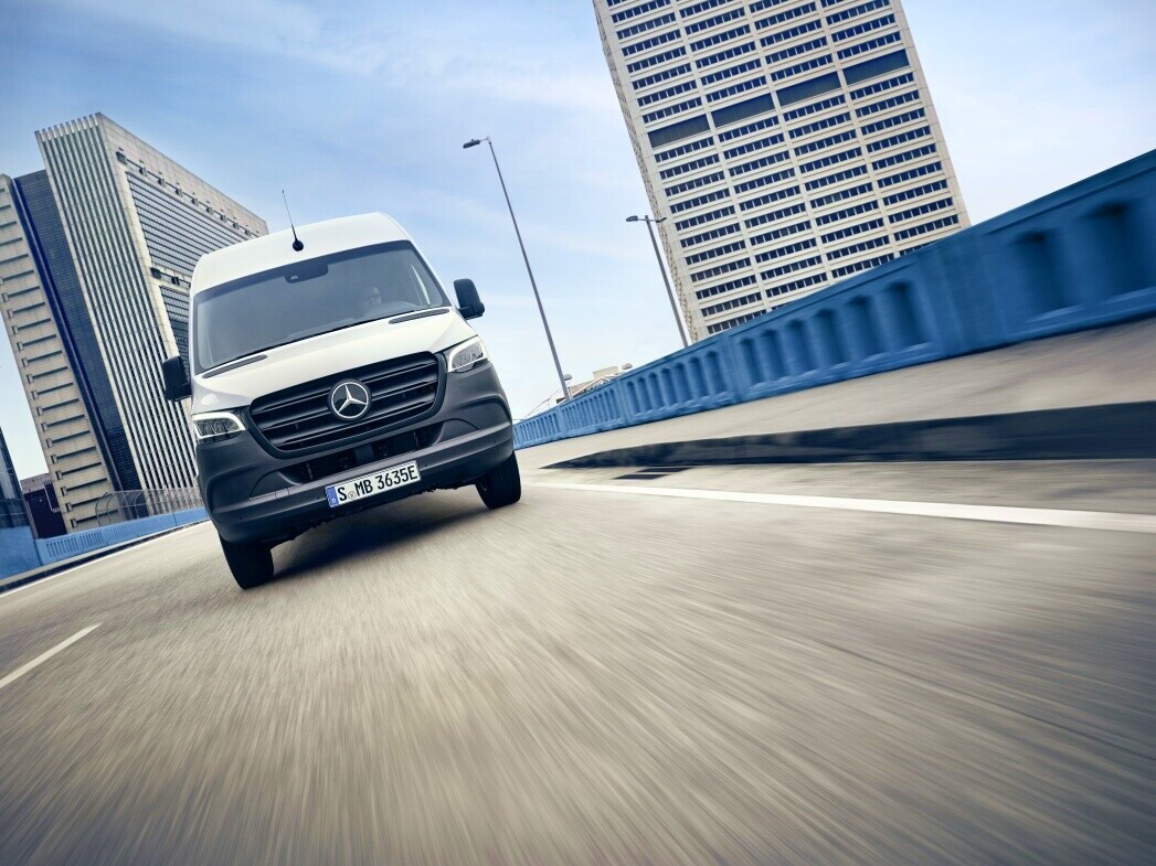 Kørsel | Mercedes-Benz Vans Hvid Mercedes-Benz eSprinter Kassevogn på betonbro med højhuse i baggrunden