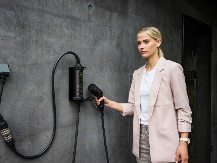 Kvinde demonstrerer det fleksible opladningssystem til Mercedes-Benz elbiler