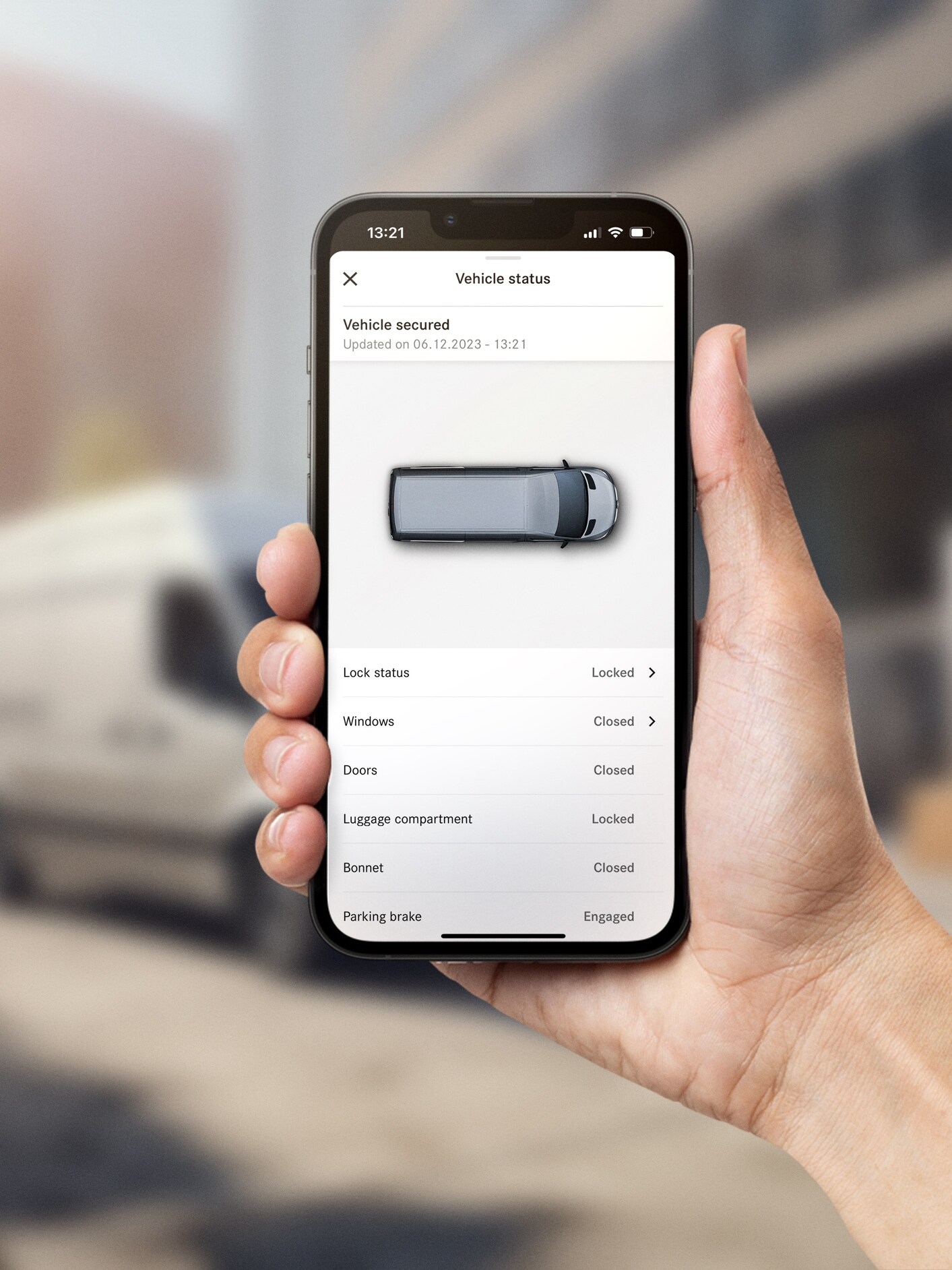 Hånd med mobiltelefon og Mercedes-Benz app med digitale tjenester