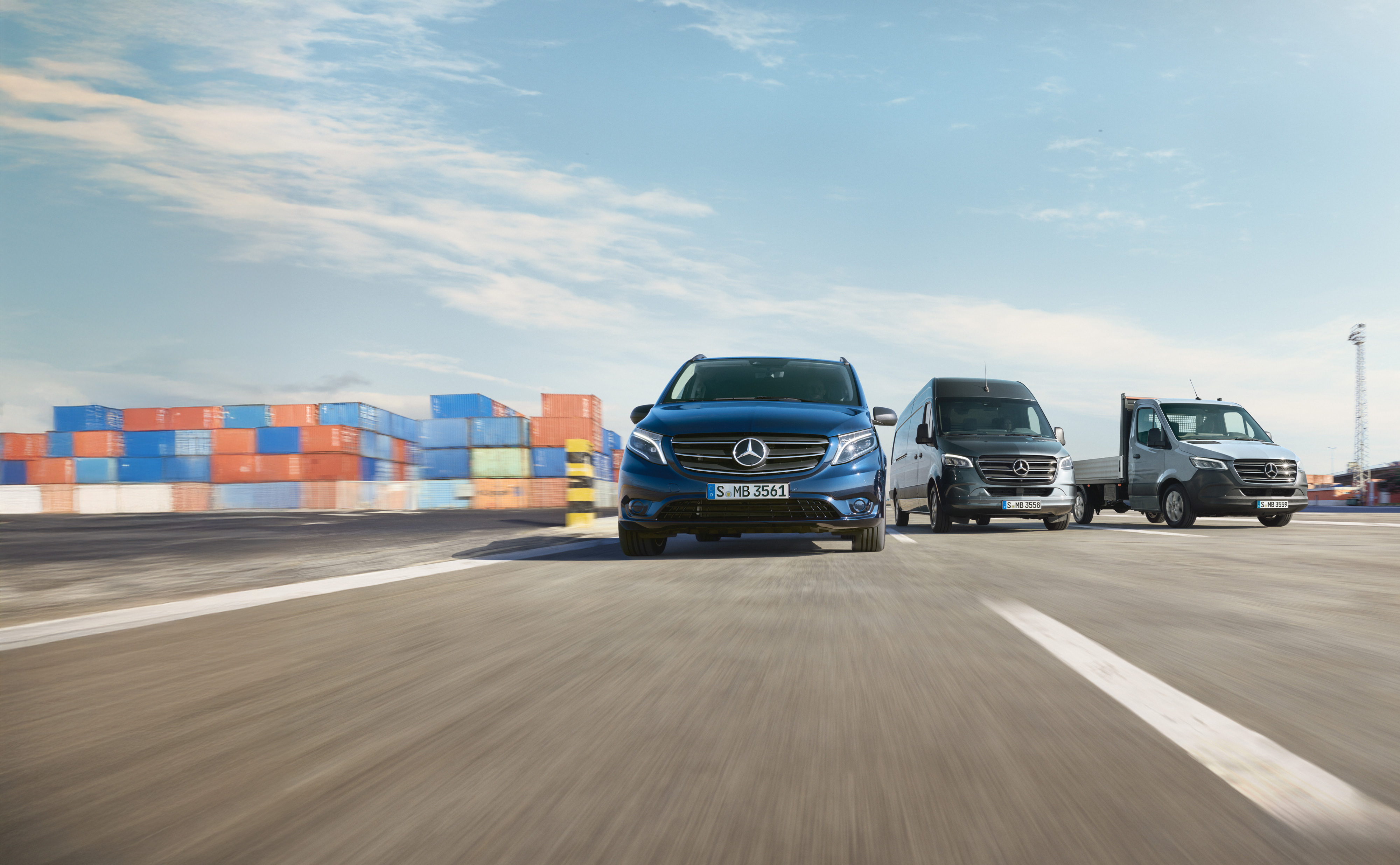 Mercedes-Benz | Vans Care | Service24h En række Mercedes-Benz varebiler parkeret side om side på en vej ved siden af en læsserampe.