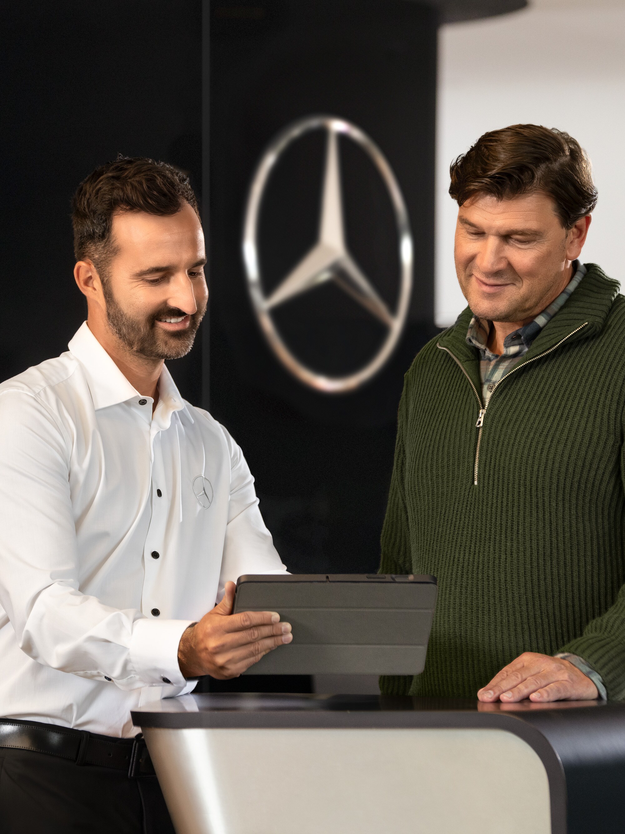 Mercedes-Benz medarbejder rådgiver kunder ved disken i et showroom.