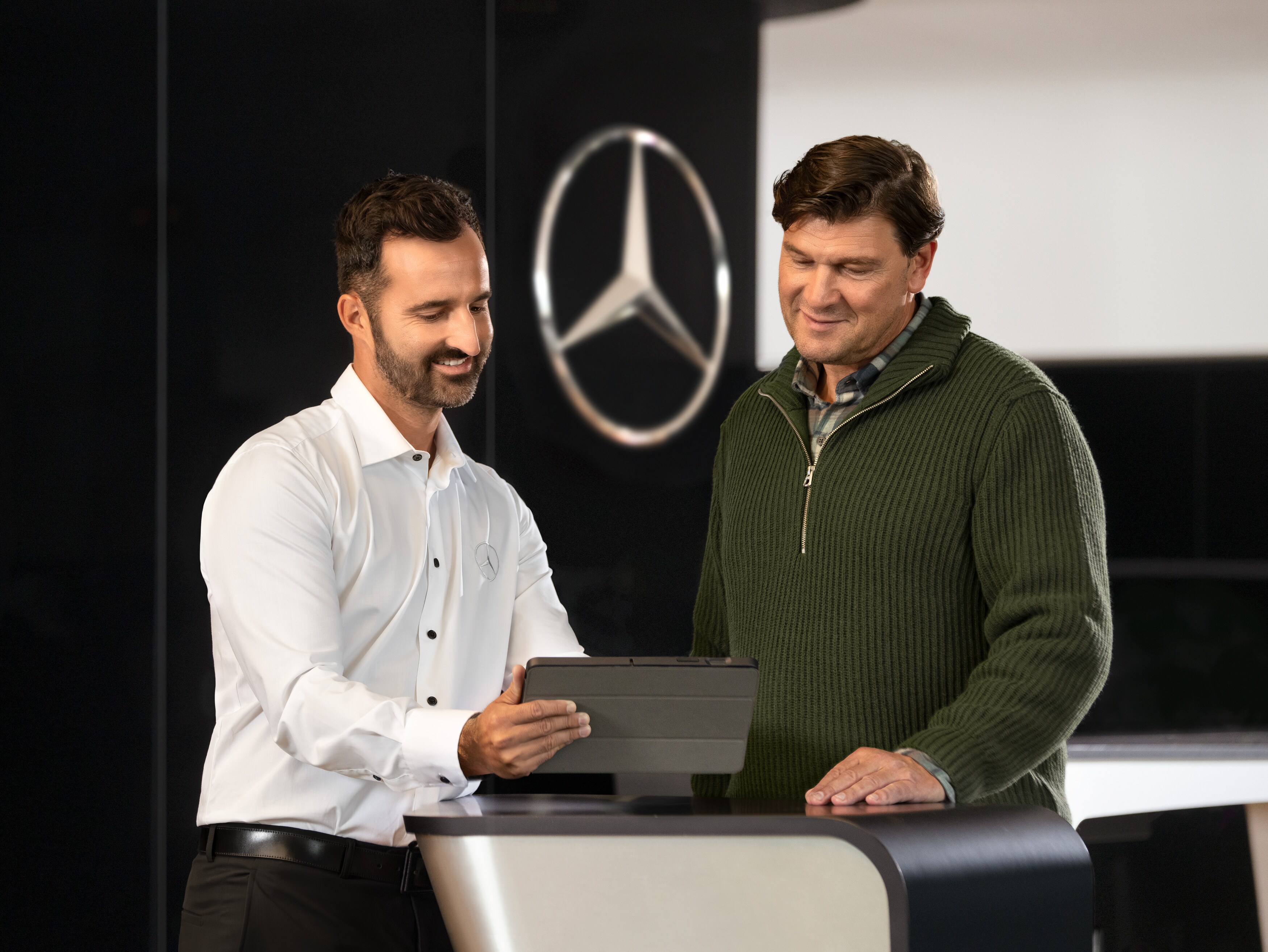 Mercedes-Benz medarbejder rådgiver kunder ved disken i et showroom.