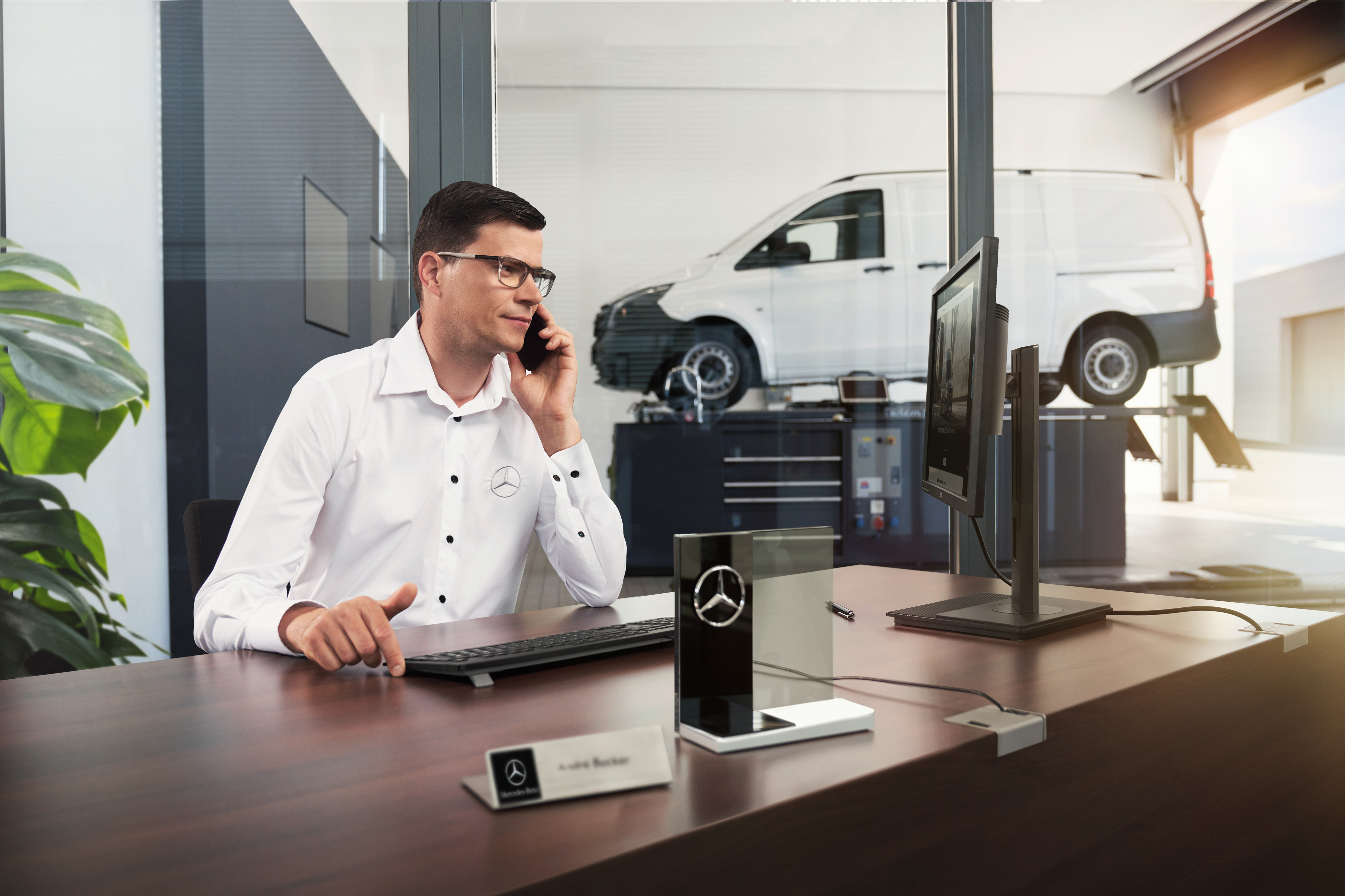 Mercedes-Benz | Bekvemmelighed | Serviceværksted Mercedes-Benz servicerådgiver taler i telefon på et værksted.