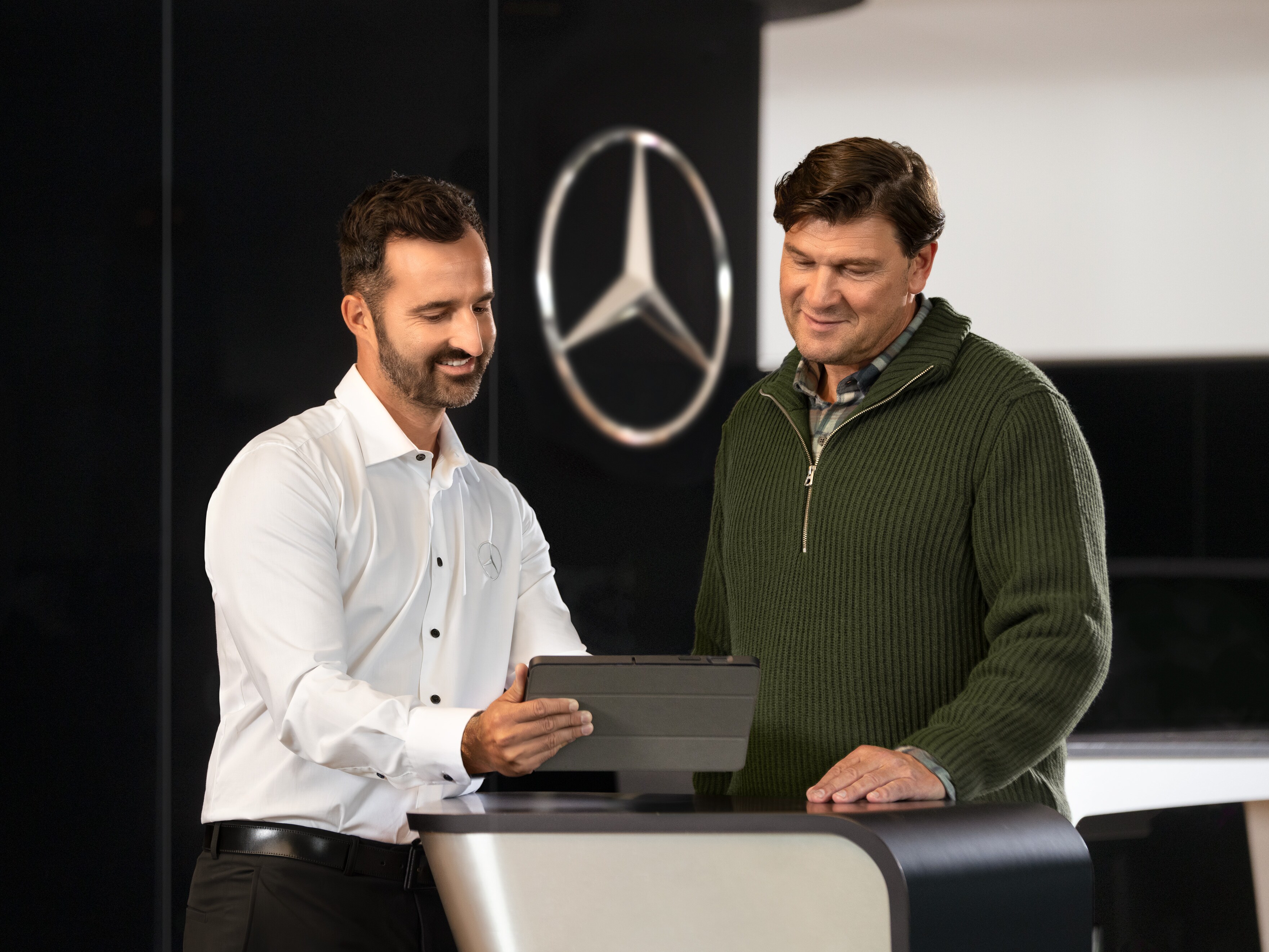 Mercedes-Benz medarbejder taler med en kunde og kigger på en tablet.