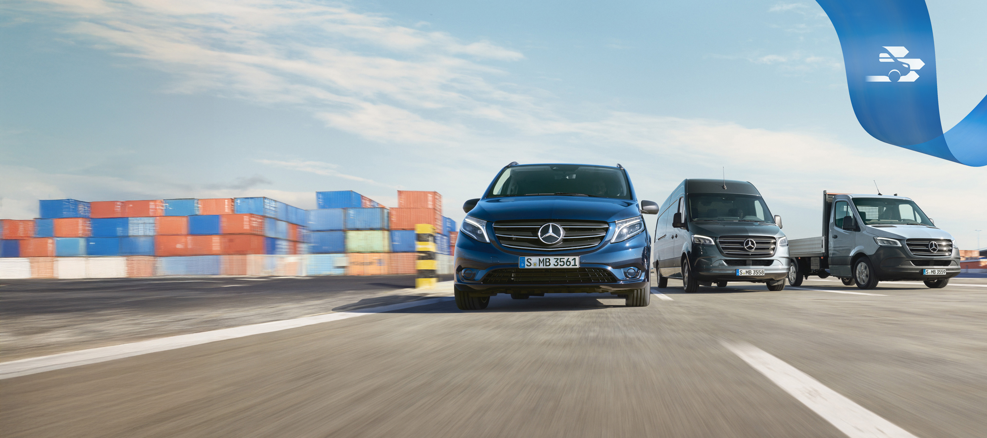 Mercedes-Benz | Bekvemmelighed MobiloVan En række Mercedes-Benz varebiler på vejen med skibscontainere i baggrunden.