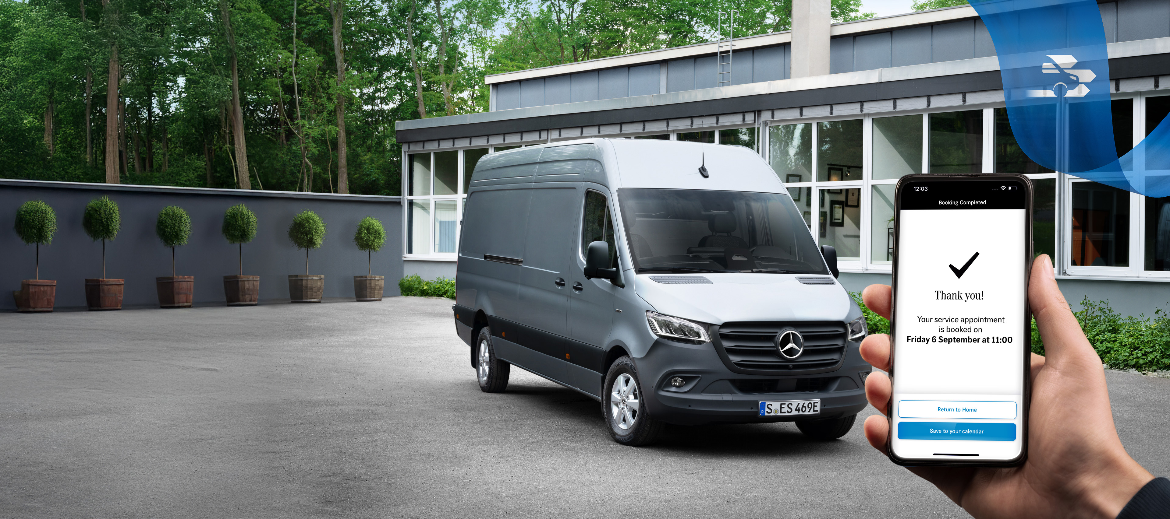 Mercedes-Benz | Online tidsbestilling En grå Mercedes-Benz Sprinter varebil foran en kontorbygning med en hånd, der holder en smartphone, i forgrunden.