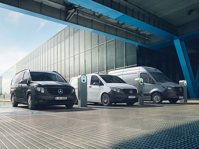 Tre elektriske Mercedes-Benz varebiler ved hver sin ladestation