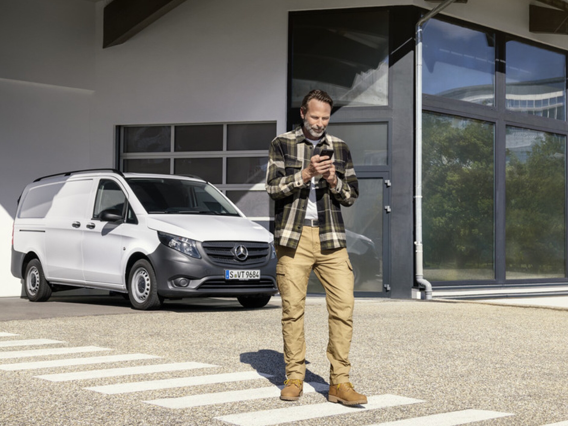 En person med en smartphone foran en Mercedes-Benz Vito.