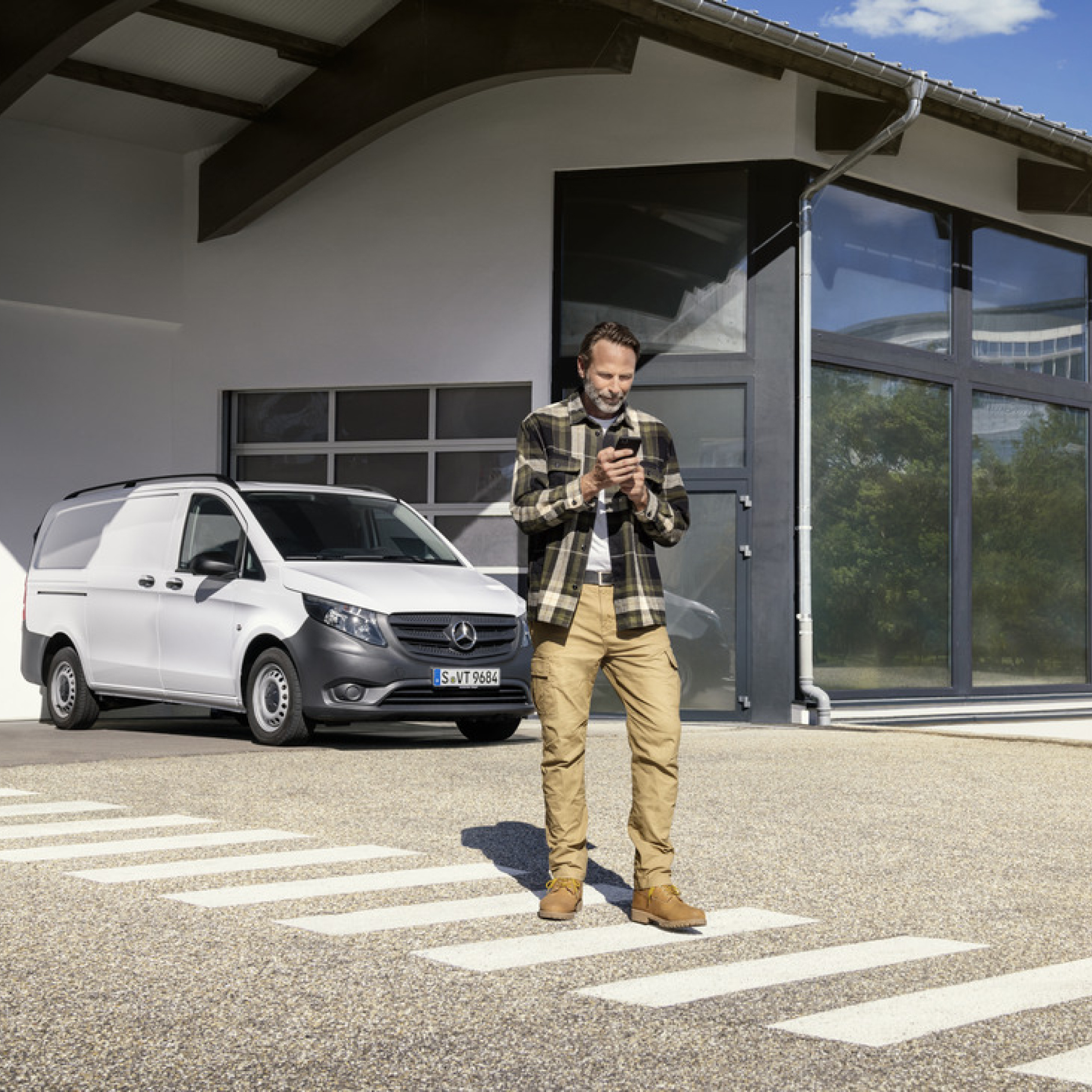 Mercedes-Benz Store | Digitale tjenester | Mercedes-Benz En person med en smartphone foran en Mercedes-Benz Vito.