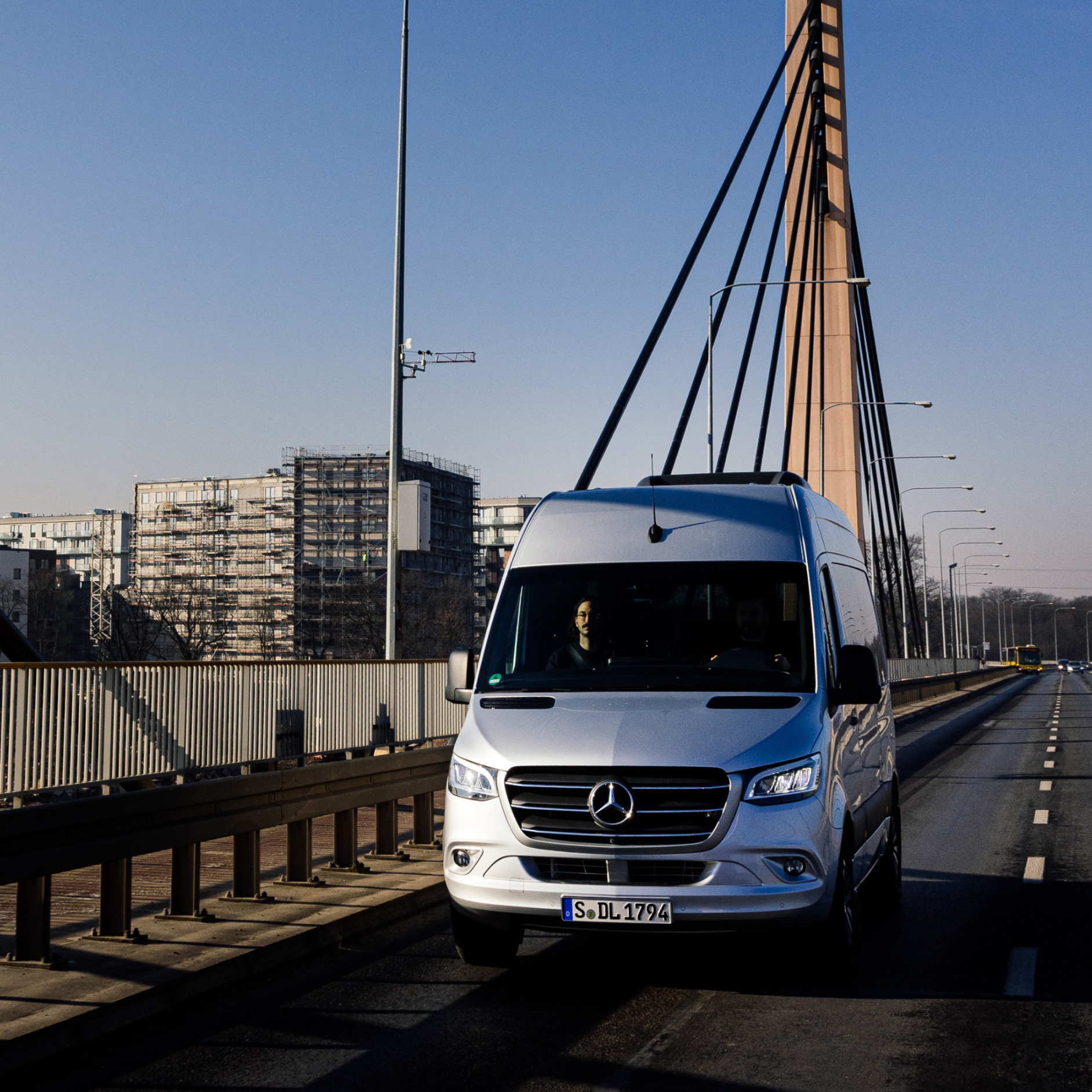 ServiceCare | Digitale tjenester | Mercedes-Benz Vans En Mercedes-Benz varebil kører over en bro med bygninger i baggrunden