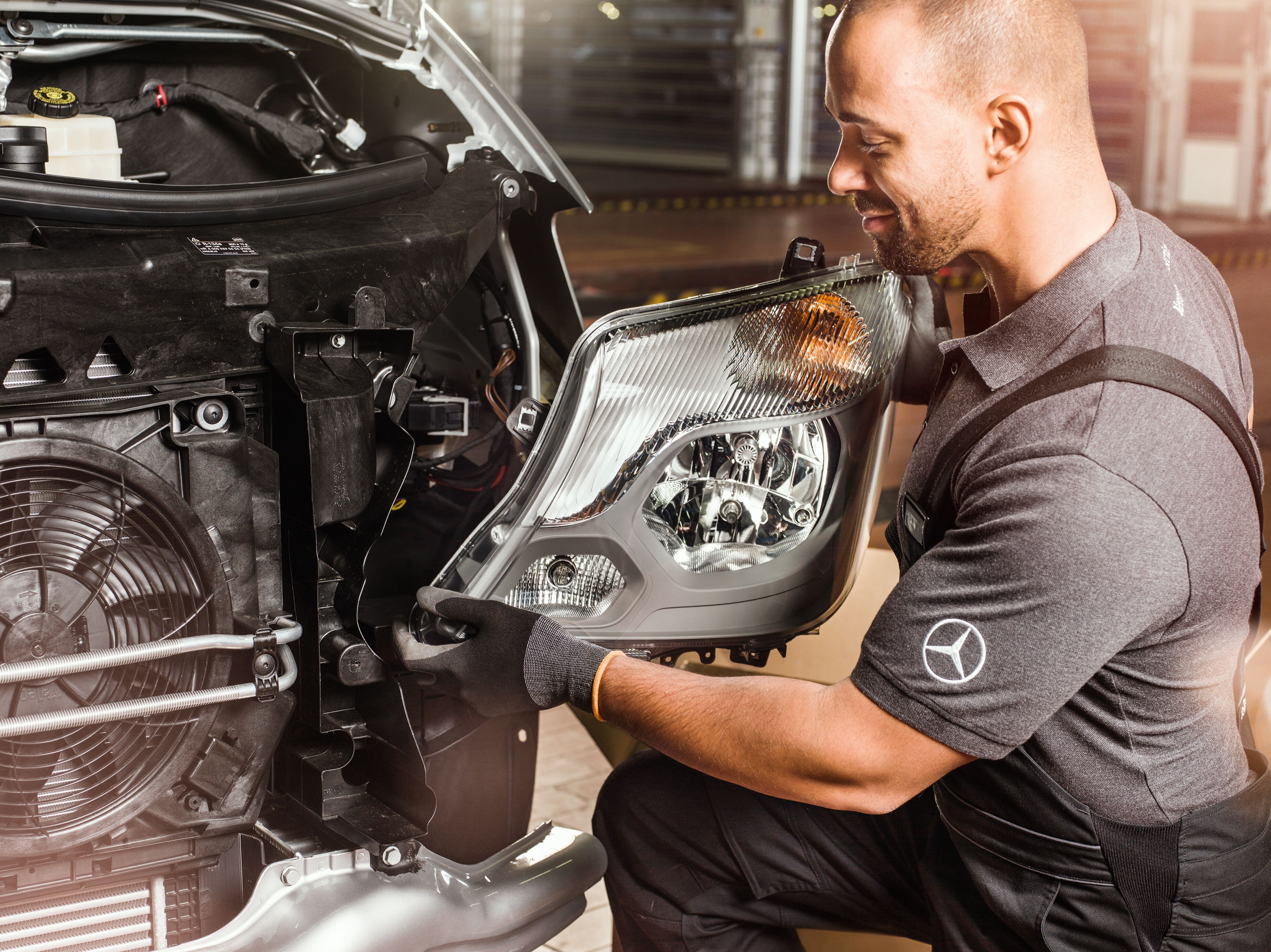 Mekaniker tjekker Mercedes-Benz originaldele foran en åben motorhjelm på en Sprinter.