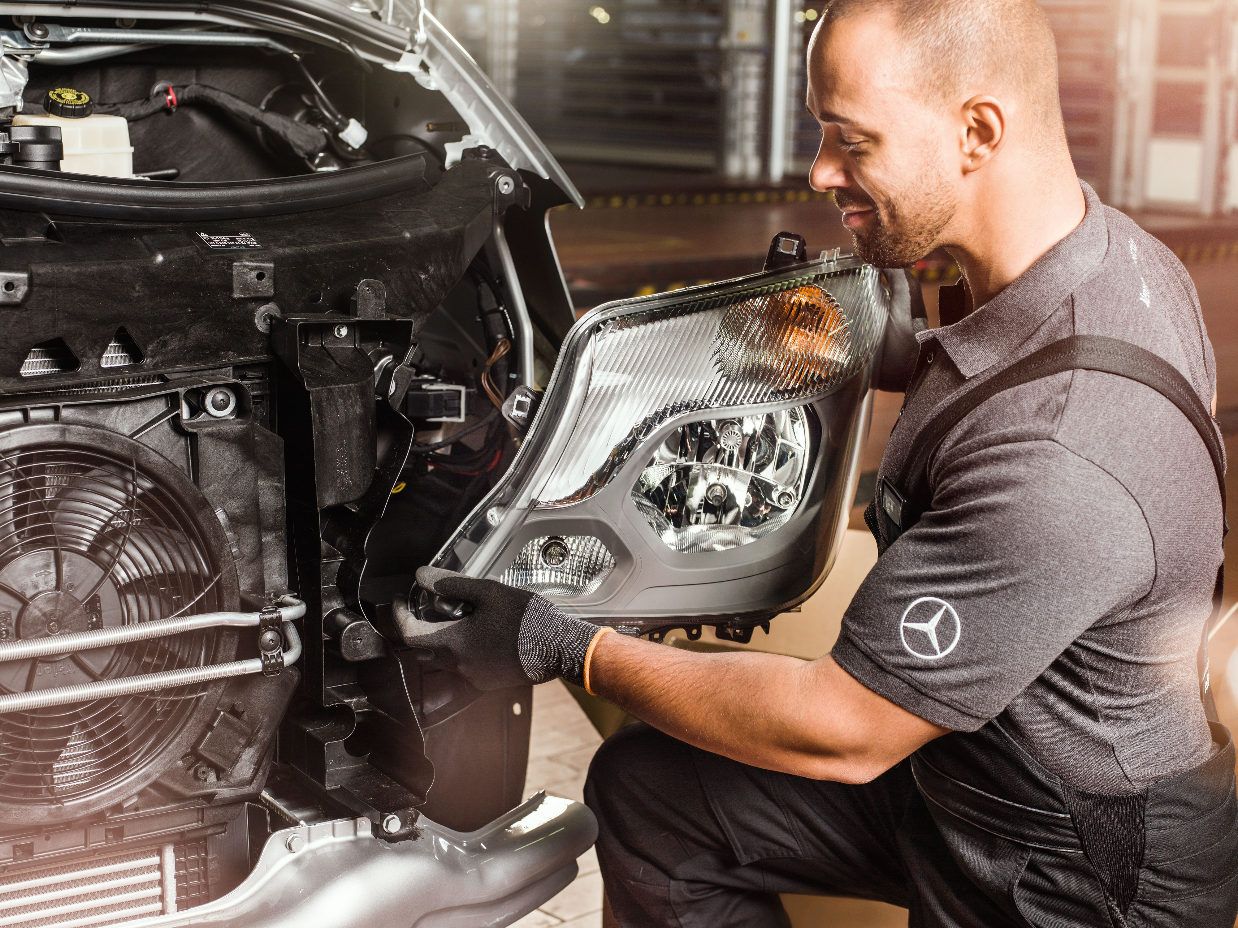 Mercedes-Benz | Originaldele til varebiler Mekaniker tjekker Mercedes-Benz originaldele foran en åben motorhjelm på en Sprinter.