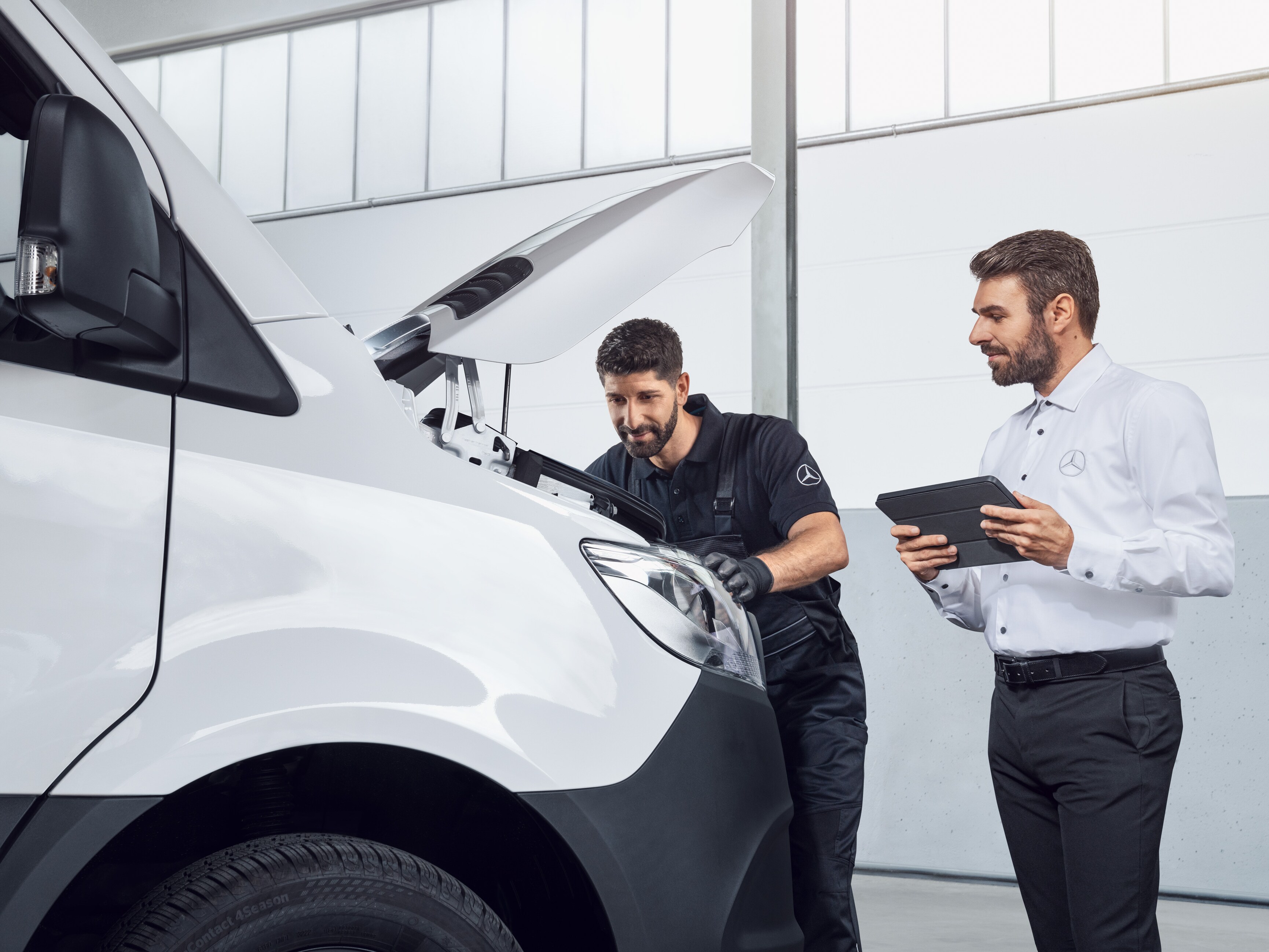 To Mercedes-Benz medarbejdere tester en Sprinter med tablet og åben motorhjelm.