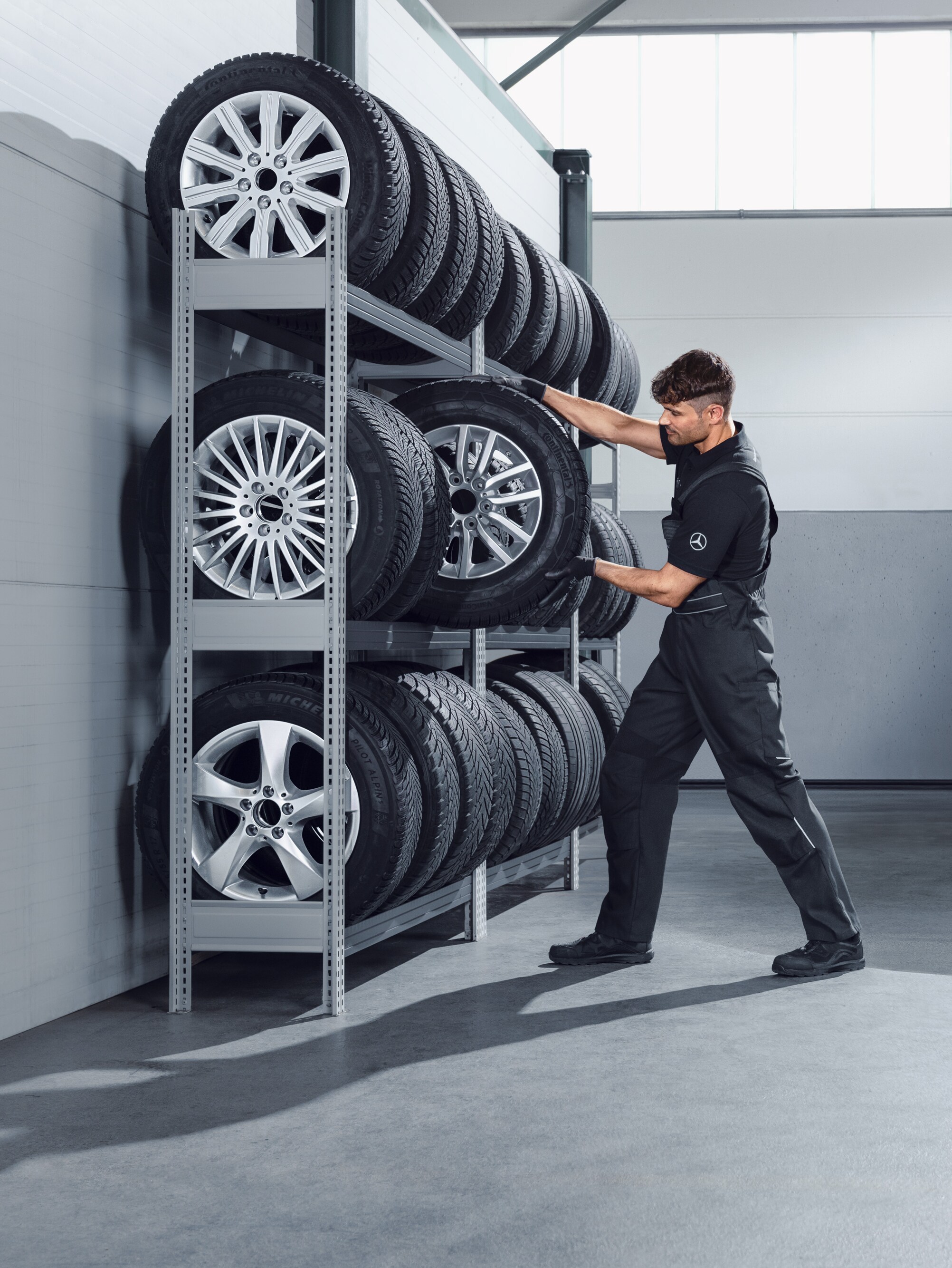 Mekaniker vælger Mercedes-Benz komplette vinterhjul fra hylden på værkstedet.