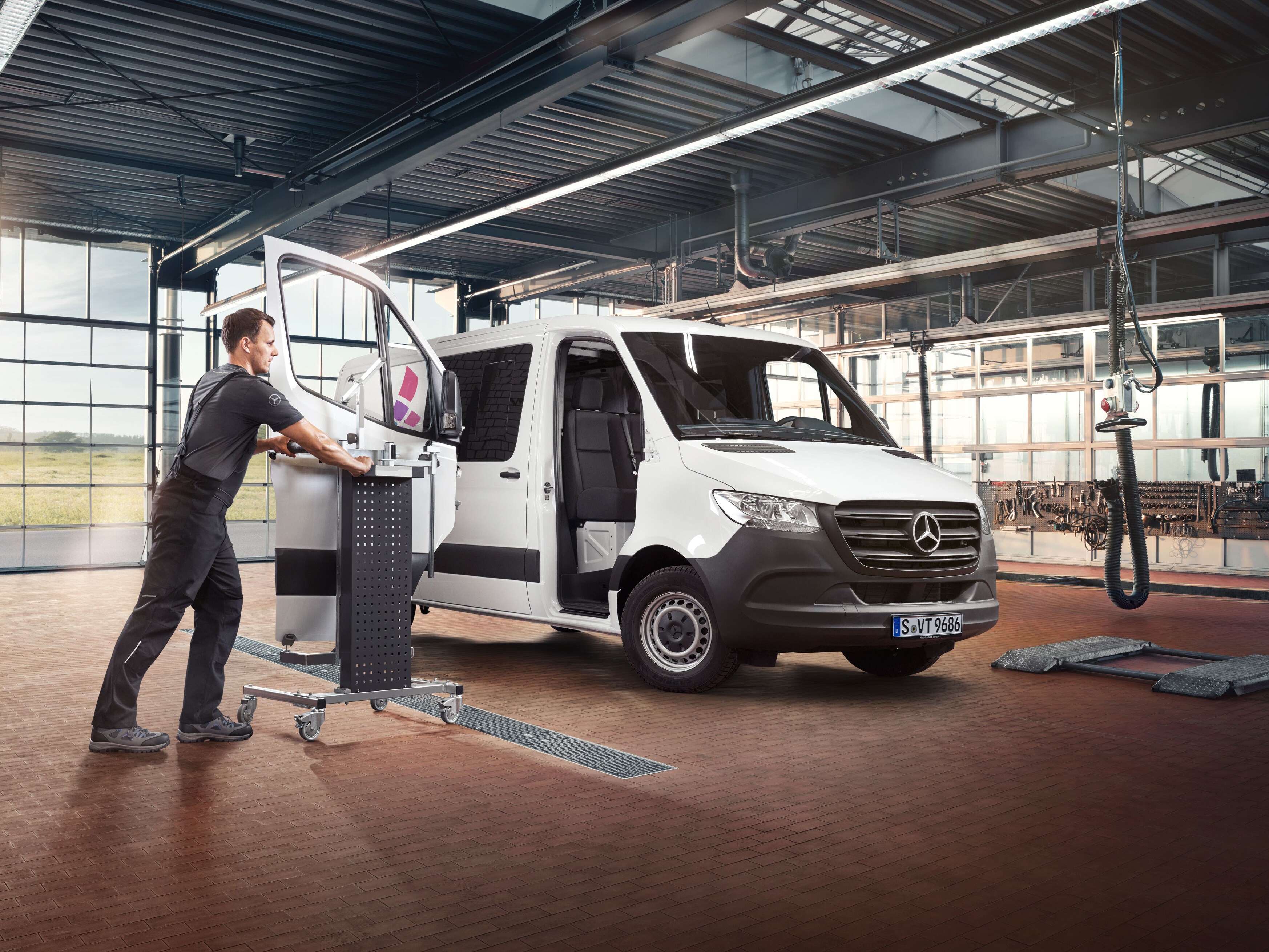 Mercedes-Benz specialist bruger specialværktøj på en varebil i et moderne værksted.