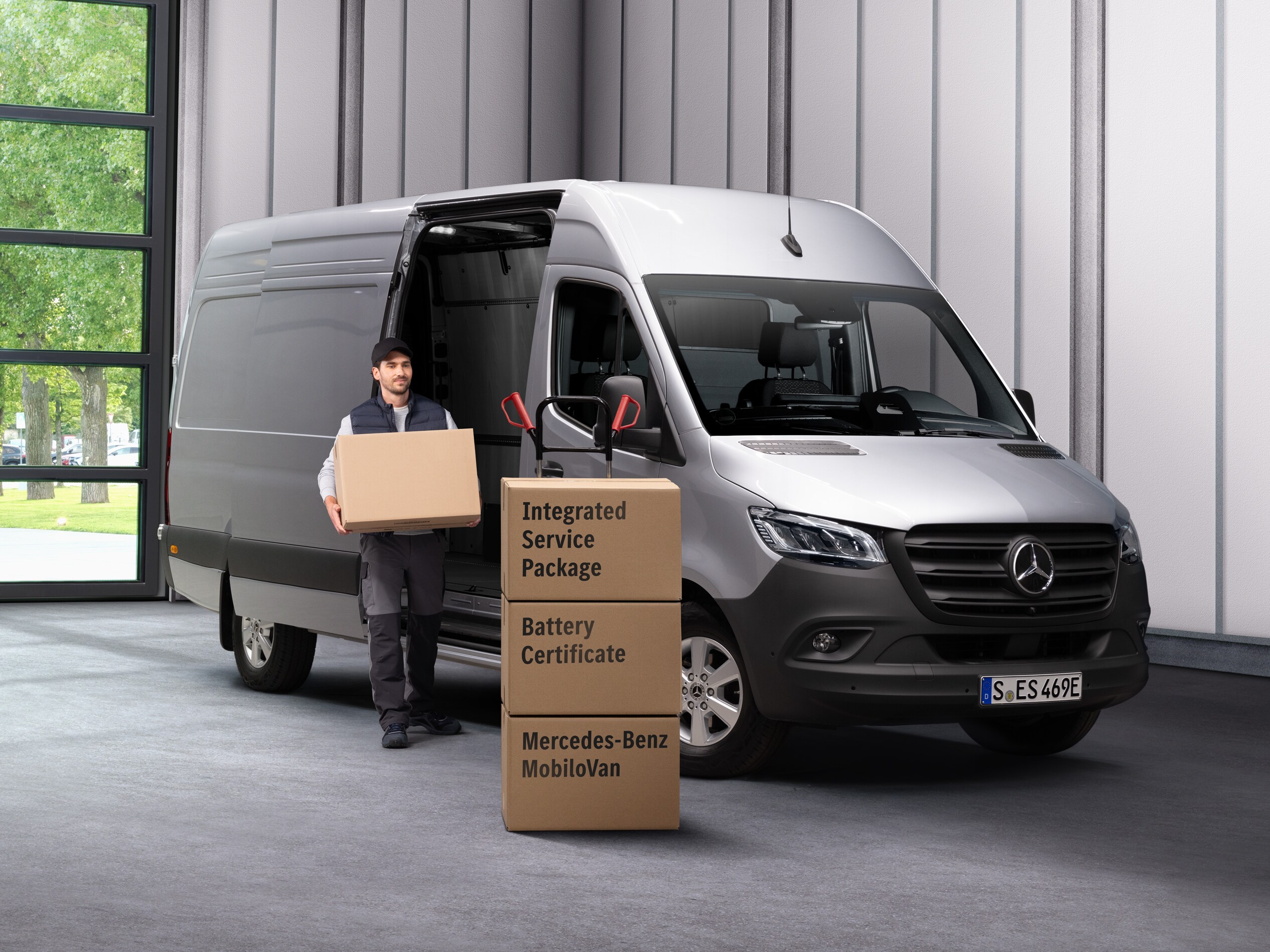 En medarbejder fra Mercedes-Benz' elektriske service bærer kasser ud af en varevogn.