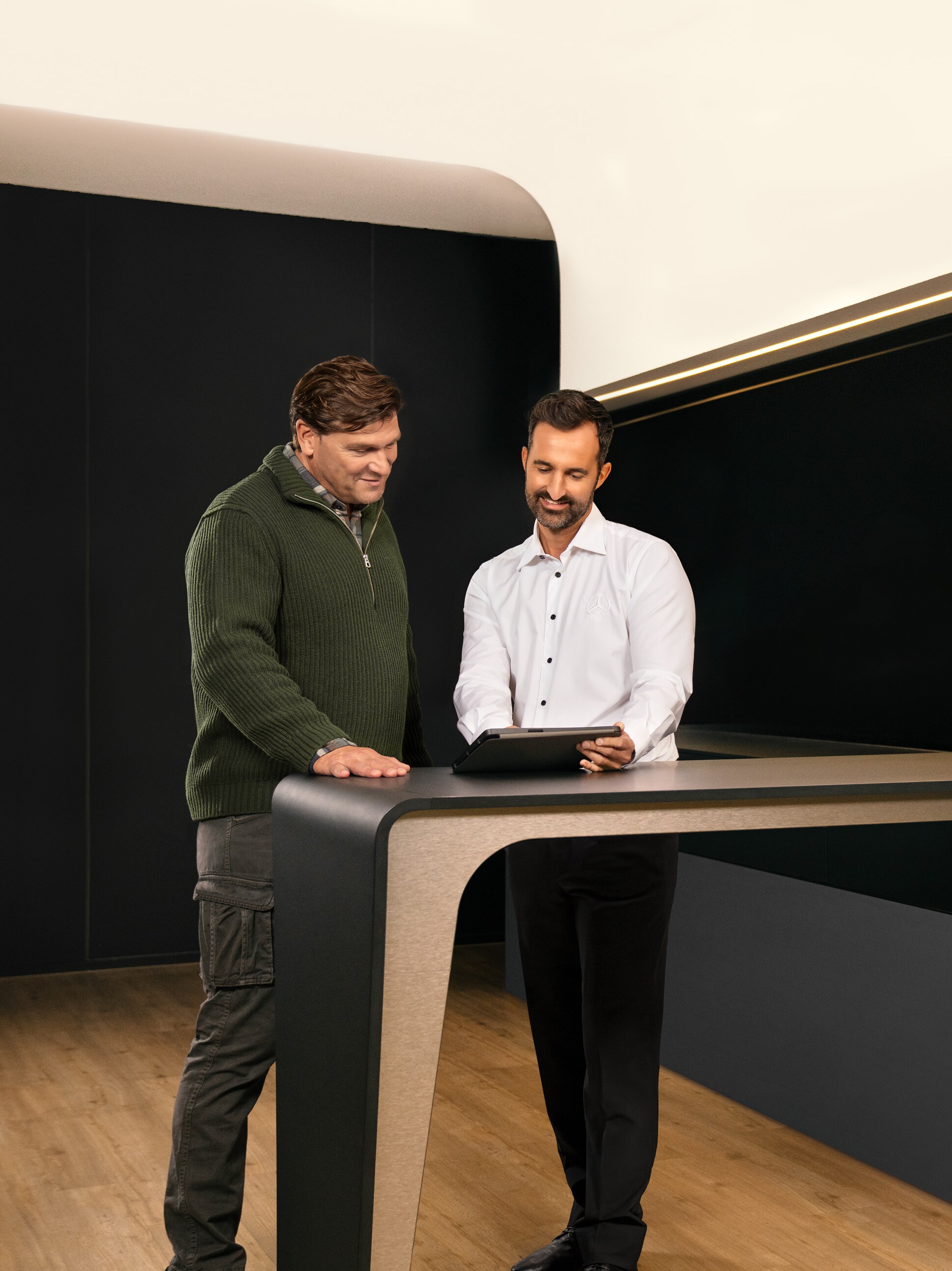 Mercedes-Benz medarbejder taler med kunde ved et bord i et showroom.