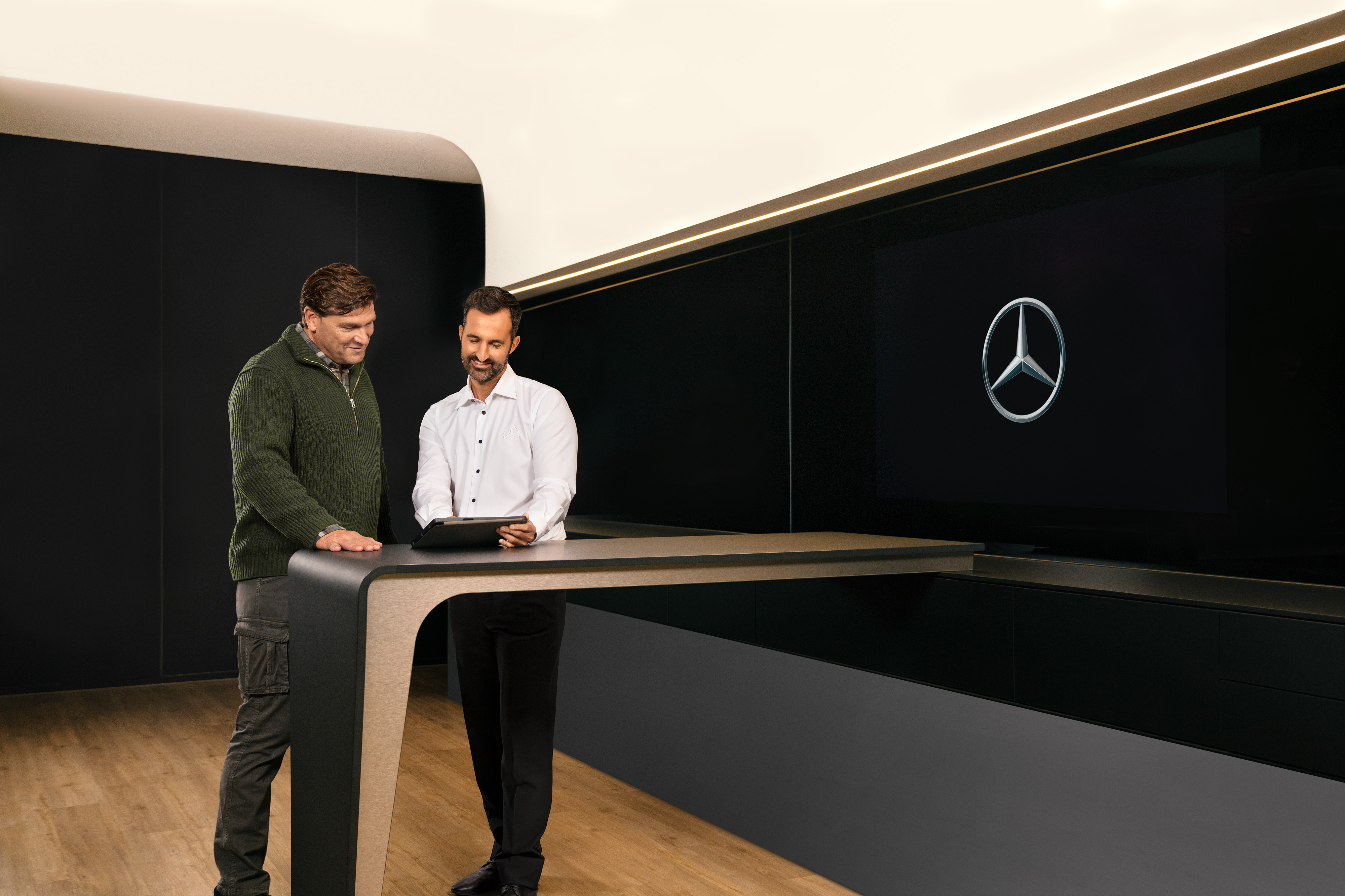 Mercedes-Benz | Varebilservice | ServiceCare Mercedes-Benz medarbejder taler med kunde ved et bord i et showroom.