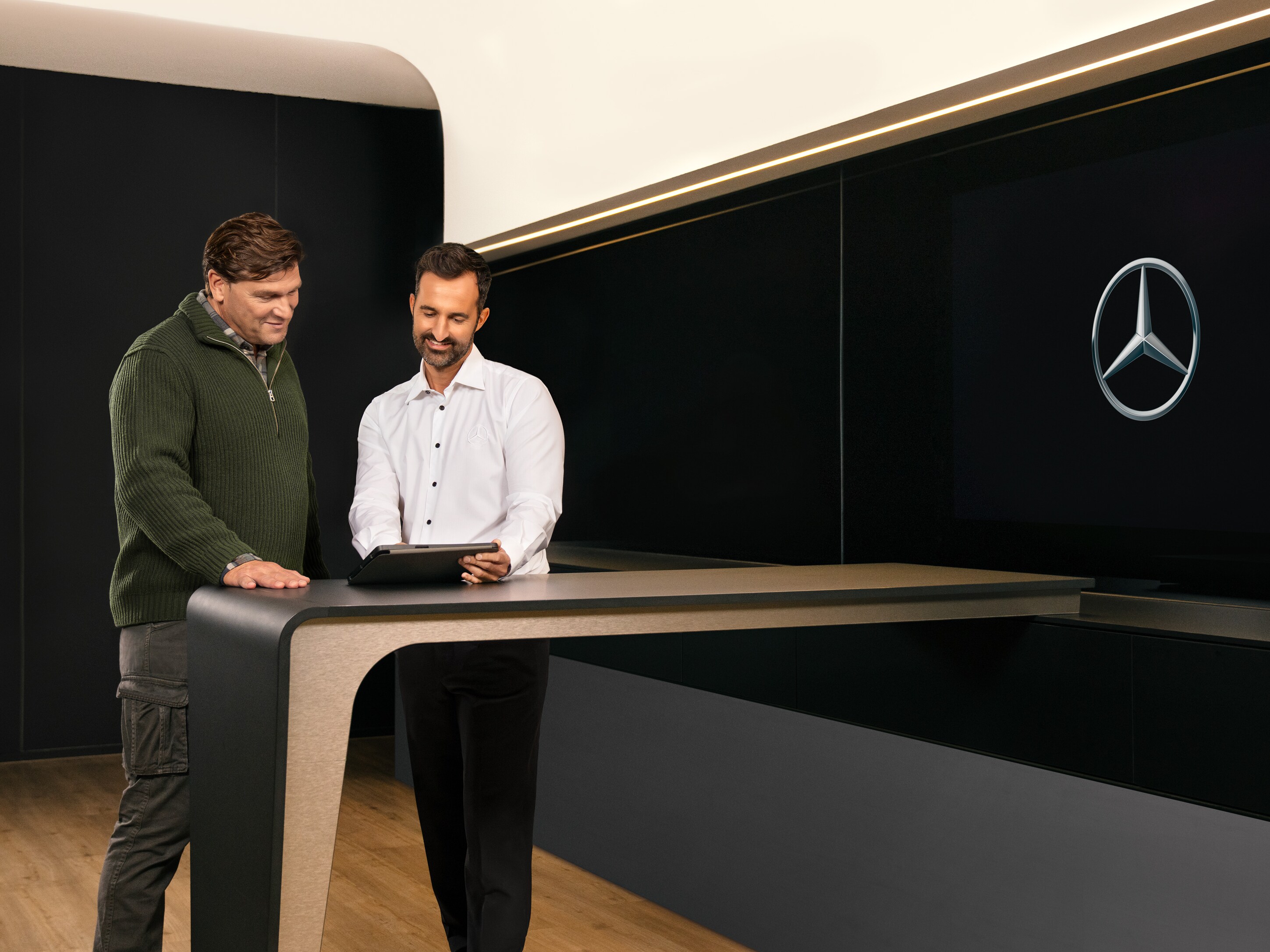 Mercedes-Benz medarbejder taler med kunde ved et bord i et showroom.