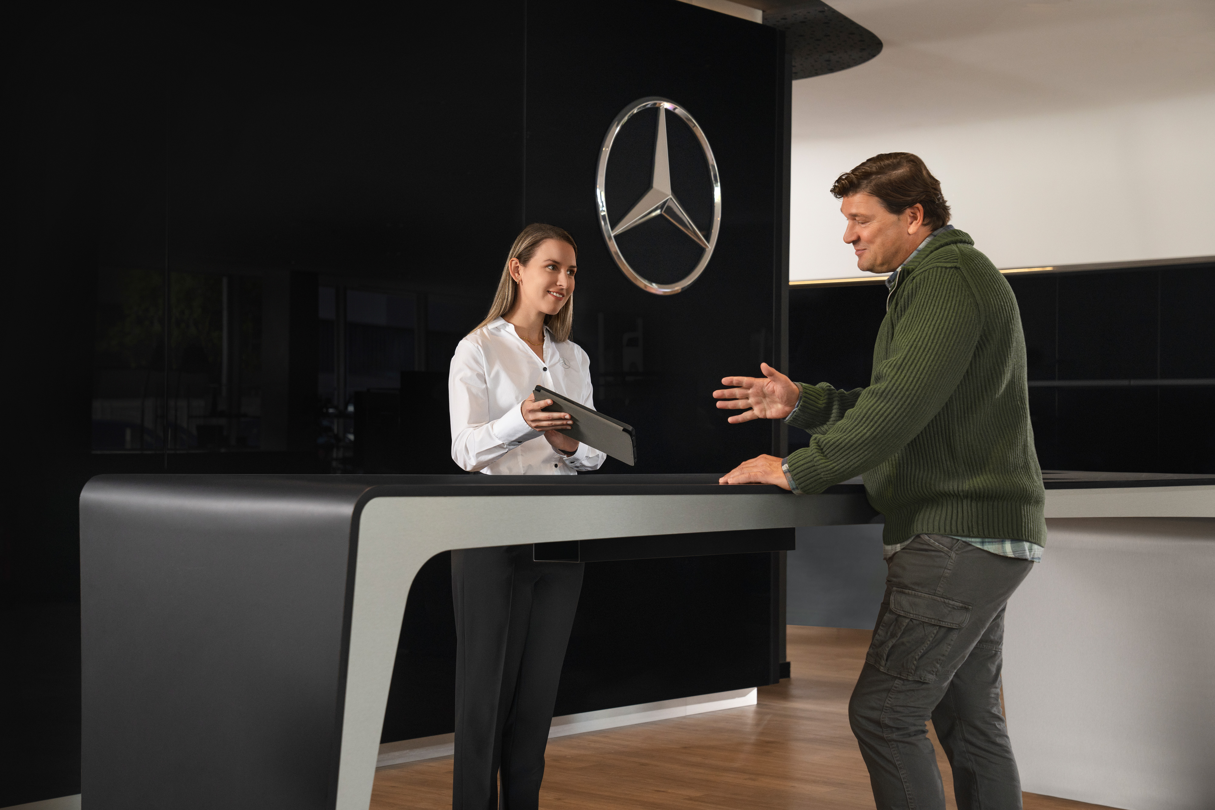 Mercedes-Benz | Service på elbiler | Rådgivning En Mercedes-Benz medarbejder rådgiver kunde i et showroom.