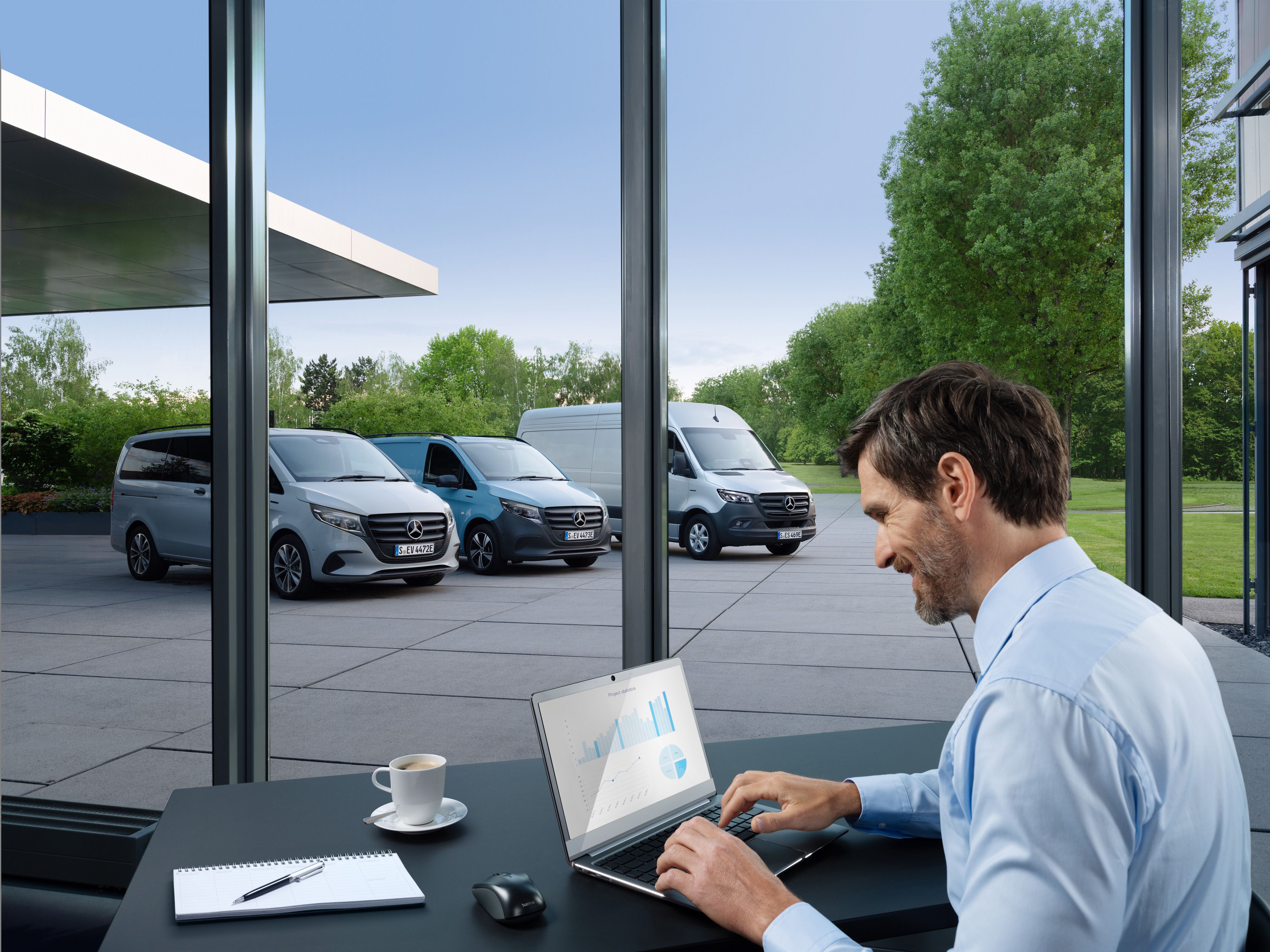 Mercedes-Benz | Service til elbiler | Pakker Mand arbejder på en computer, udenfor er der en række Mercedes-Benz varebiler.