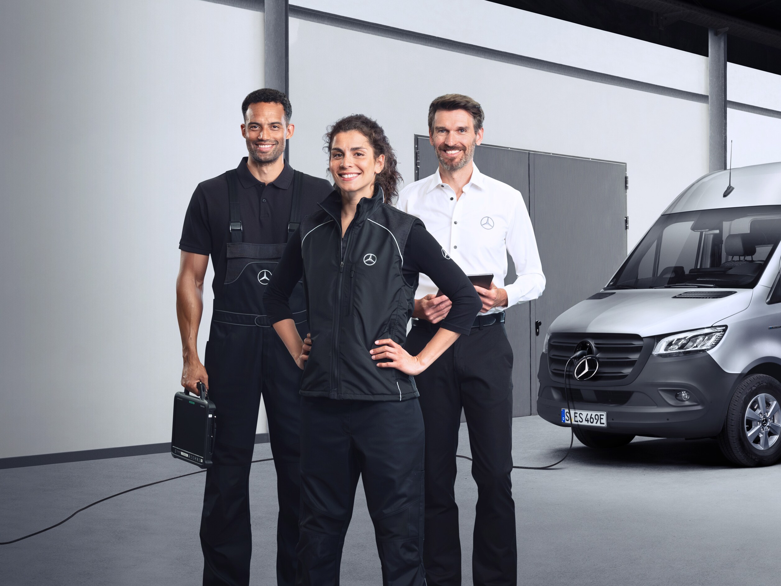 Tre medarbejdere foran en elektrisk Mercedes-Benz Sprinter varebil med isat ladekabel.