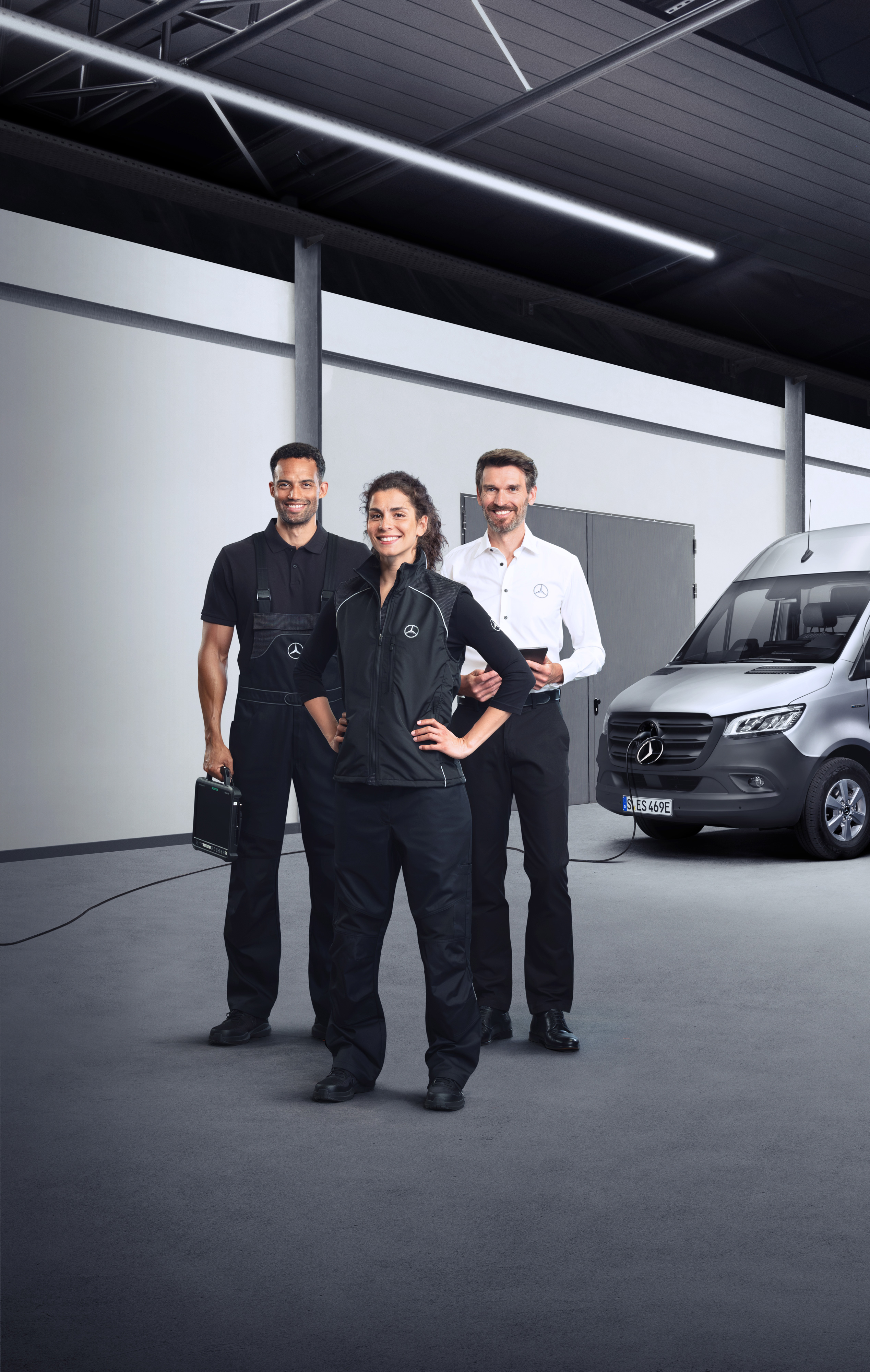 Mercedes-Benz | Service på elbiler Tre medarbejdere foran en elektrisk Mercedes-Benz Sprinter varebil med isat ladekabel.