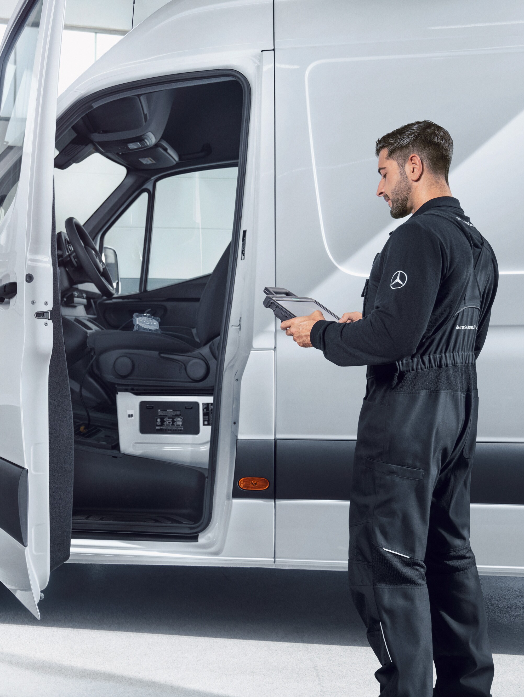 En tekniker udfører servicetjek på en hvid Mercedes-Benz Sprinter Varebil.