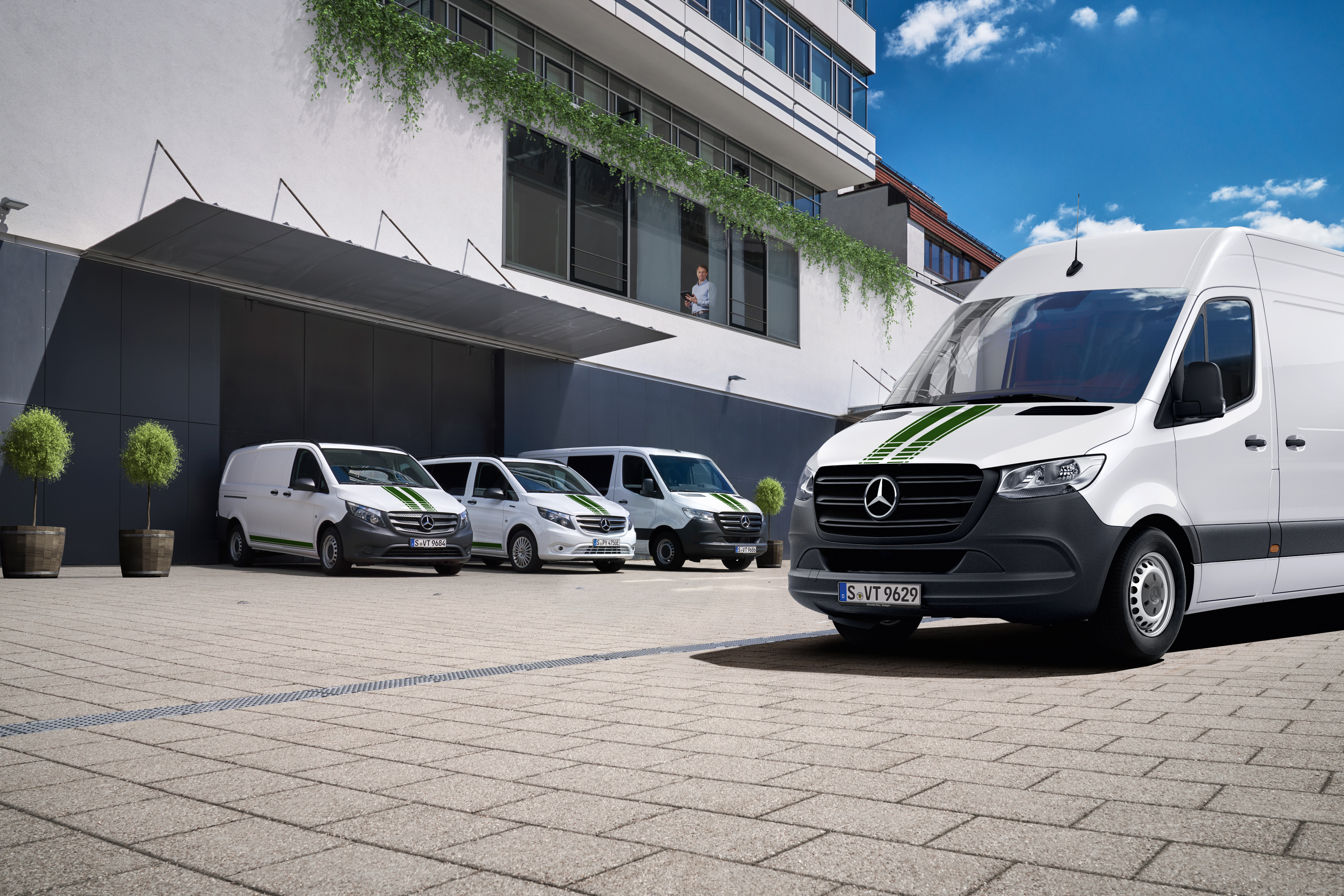 Mercedes-Benz | Flådetjenester til varebiler En flåde af hvide Mercedes-Benz varebiler foran en kontorbygning.