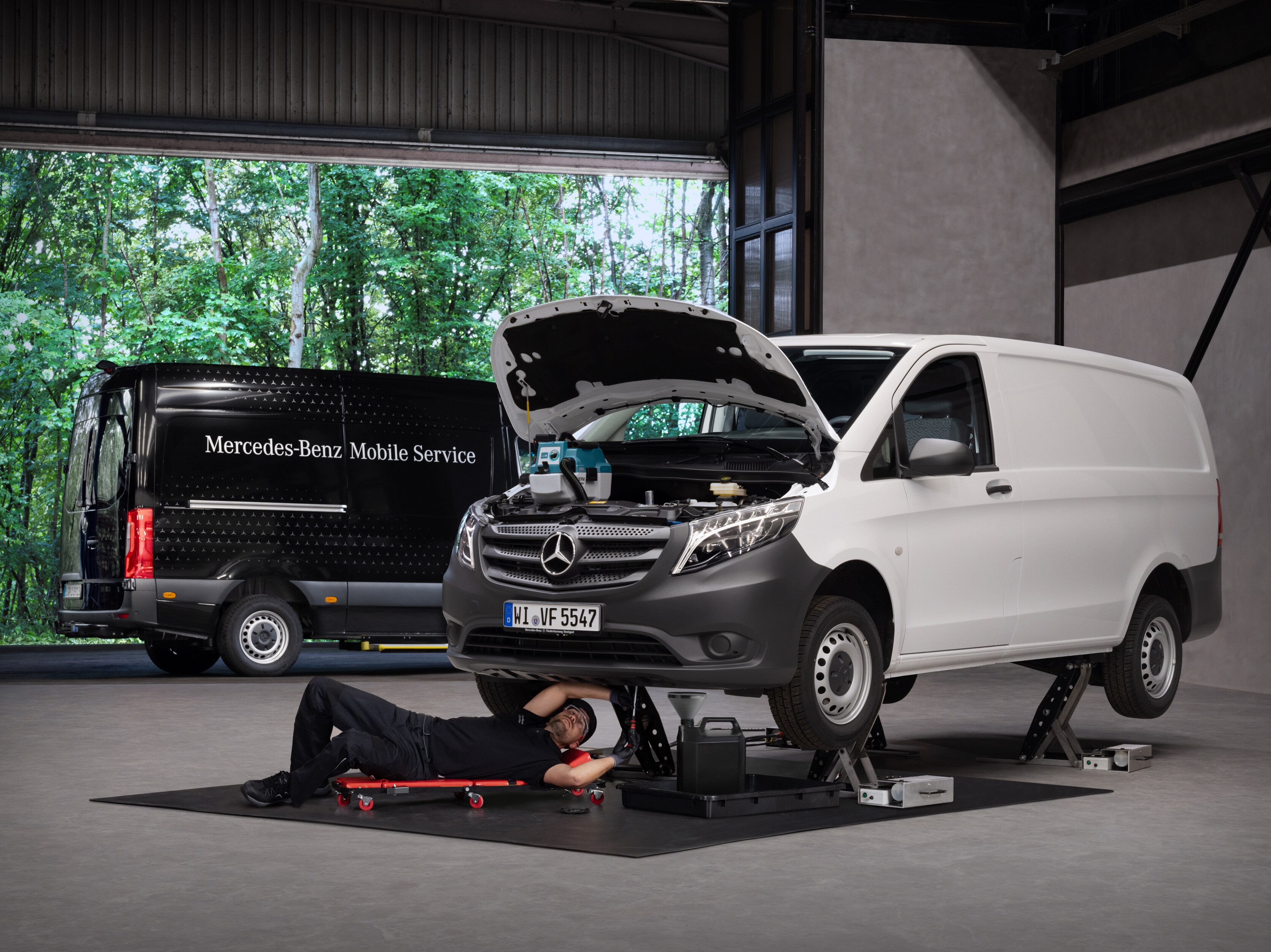 En tekniker reparerer en hvid Mercedes-Benz Vito varebil på et værksted.