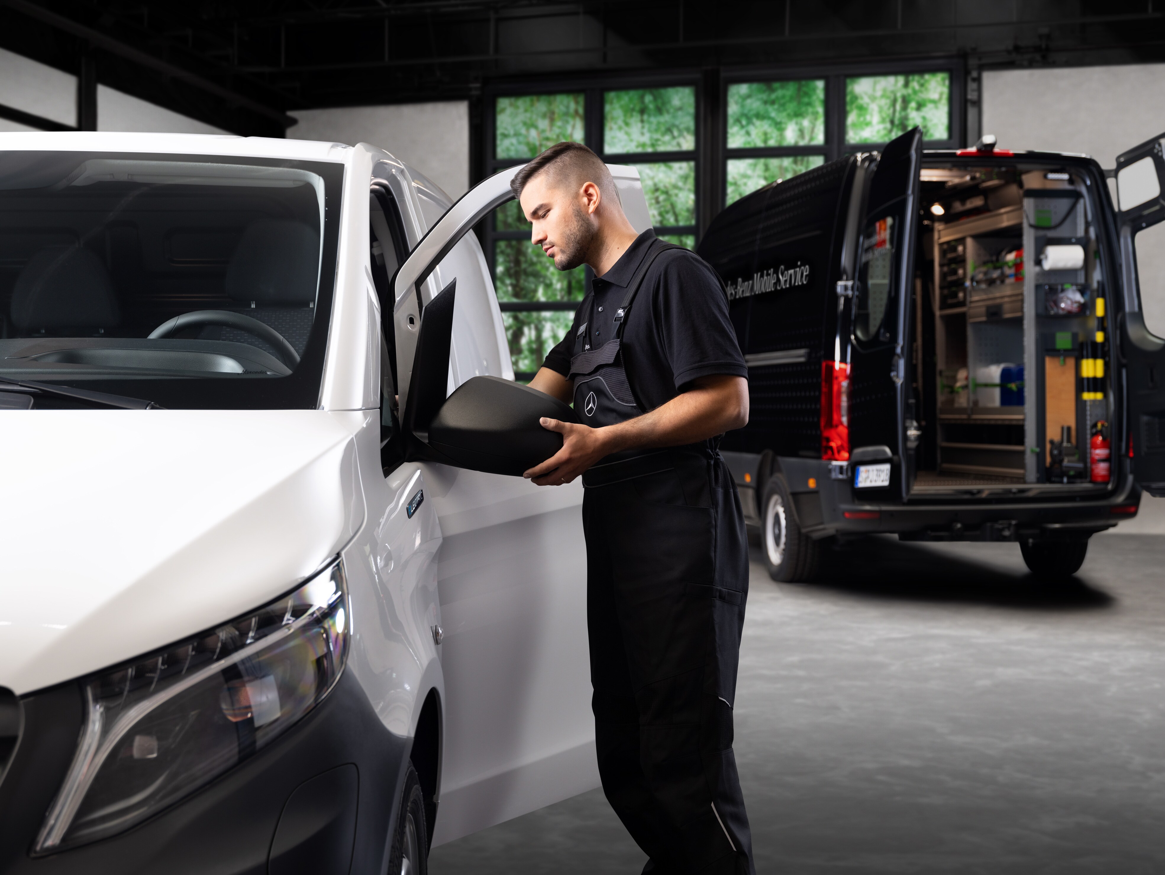En tekniker udskifter et sidespejl på en hvid Mercedes-Benz Vito varebil.