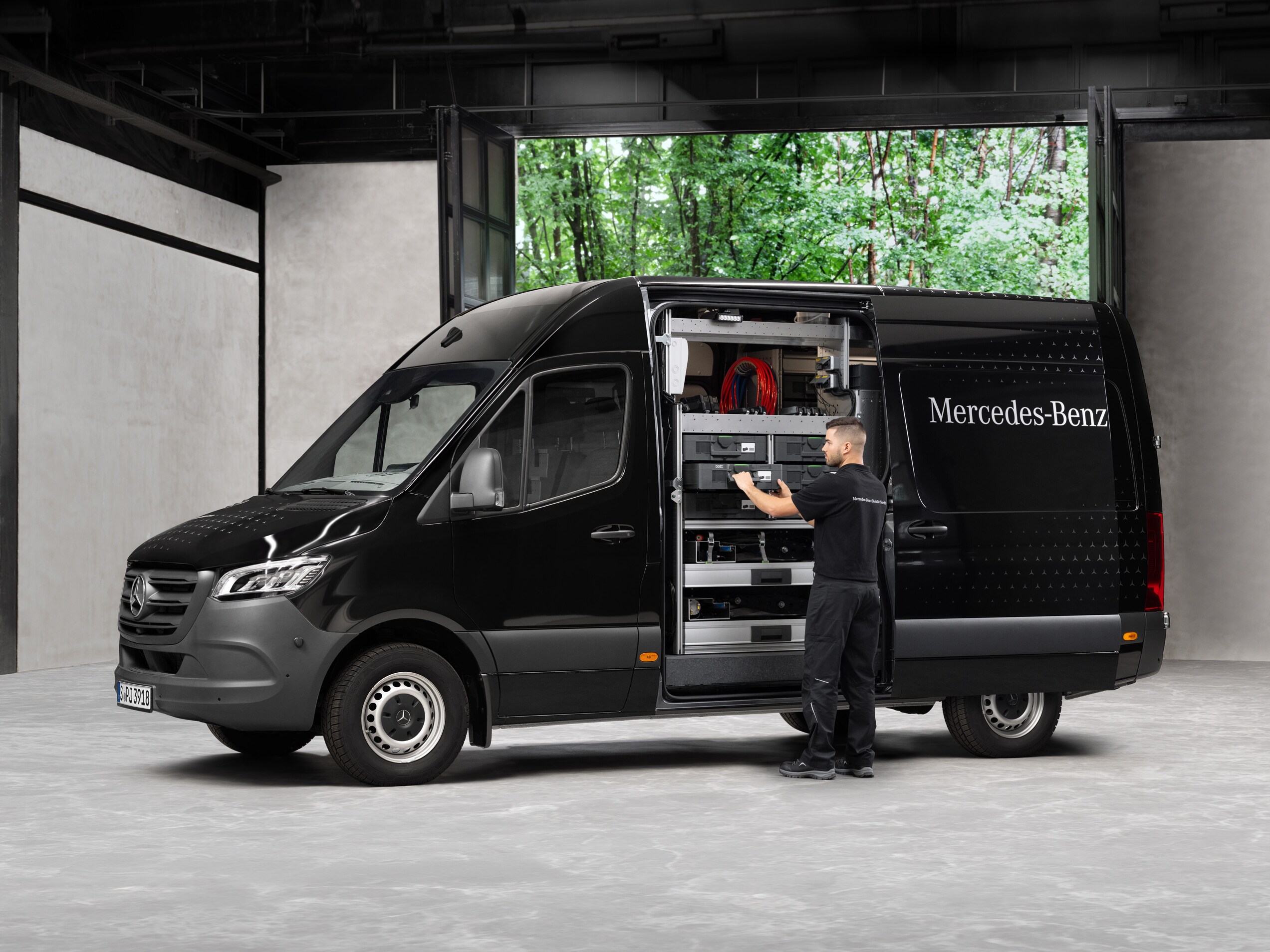 En tekniker fjerner værktøj fra en sort Mercedes-Benz Sprinter varebil.