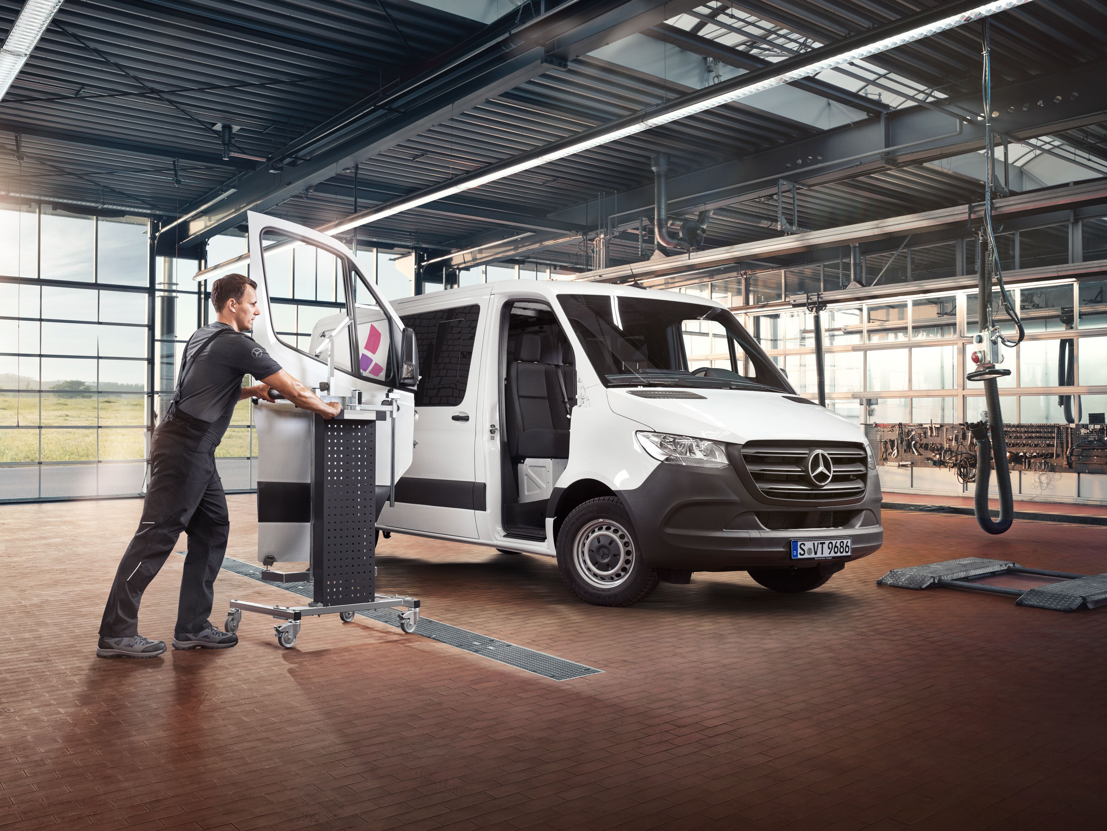 Mekaniker monterer døren på en hvid Mercedes-benz Sprinter.