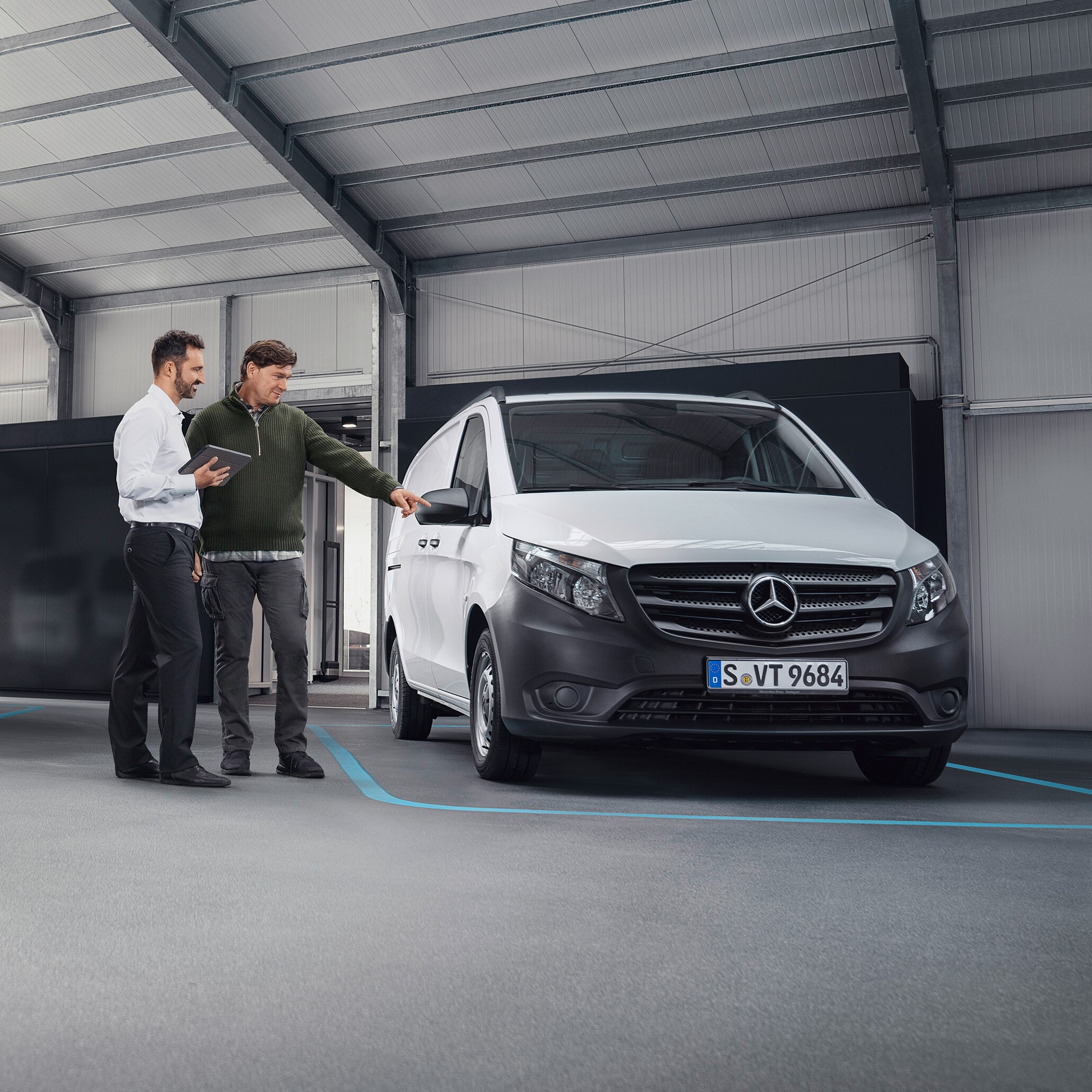 Mercedes-Benz kundeservicemedarbejder med kunde hos en servicepartner foran en varebil.