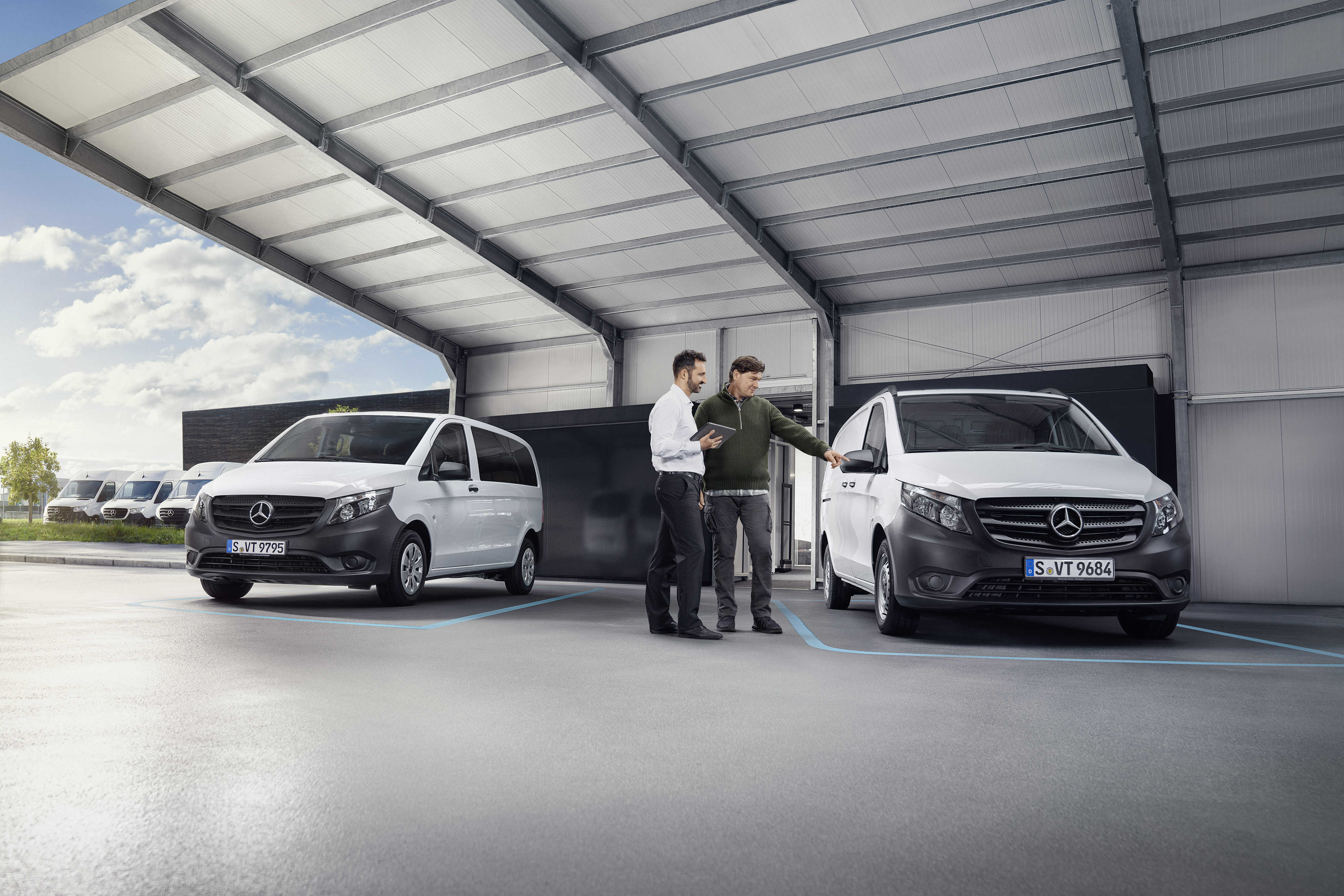 Mercedes-Benz | Tilbagekaldelse Mercedes-Benz kundeservicemedarbejder med kunde hos en servicepartner foran en varebil.