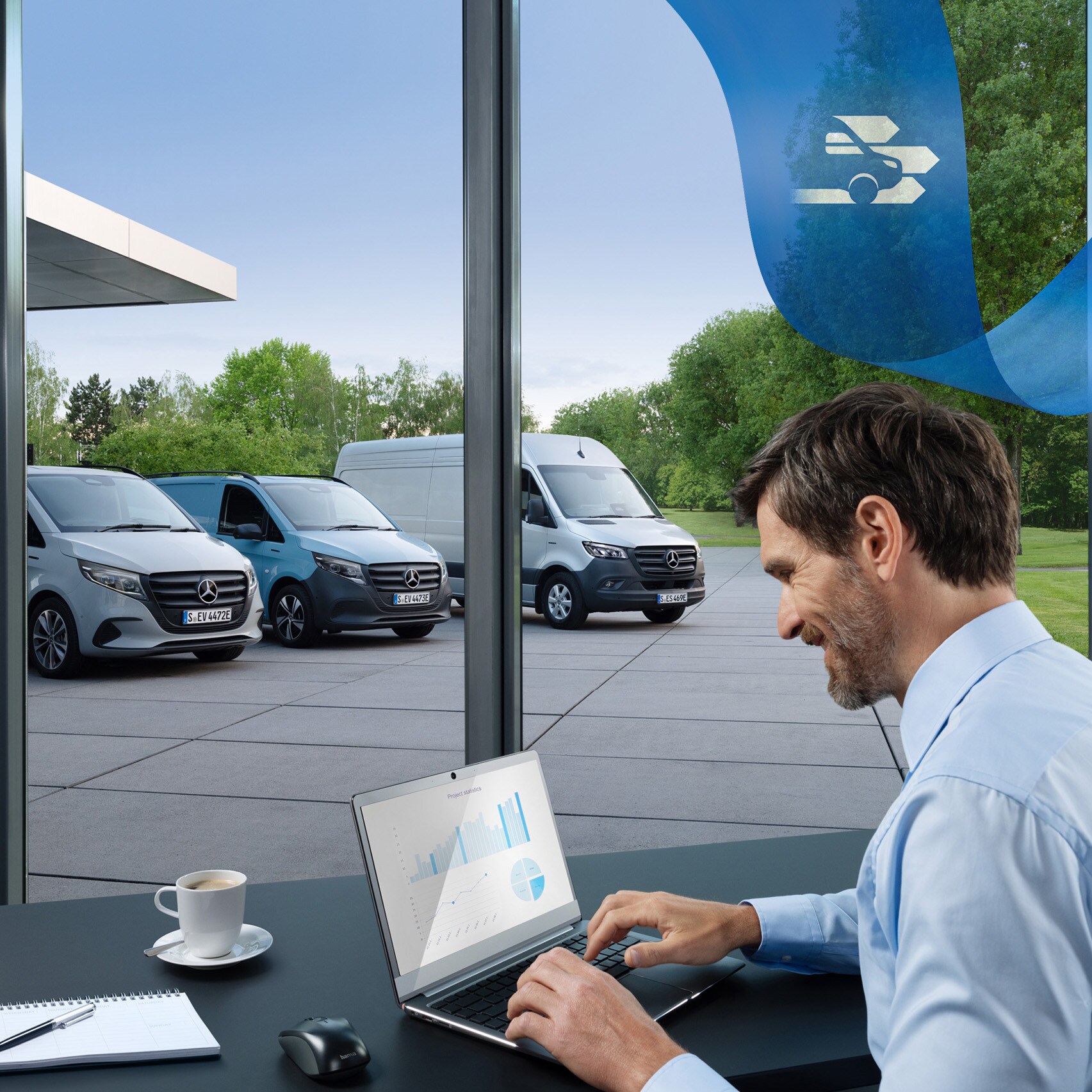 Mand bruger computer på kontor med Mercedes-Benz varebiler i baggrunden.
