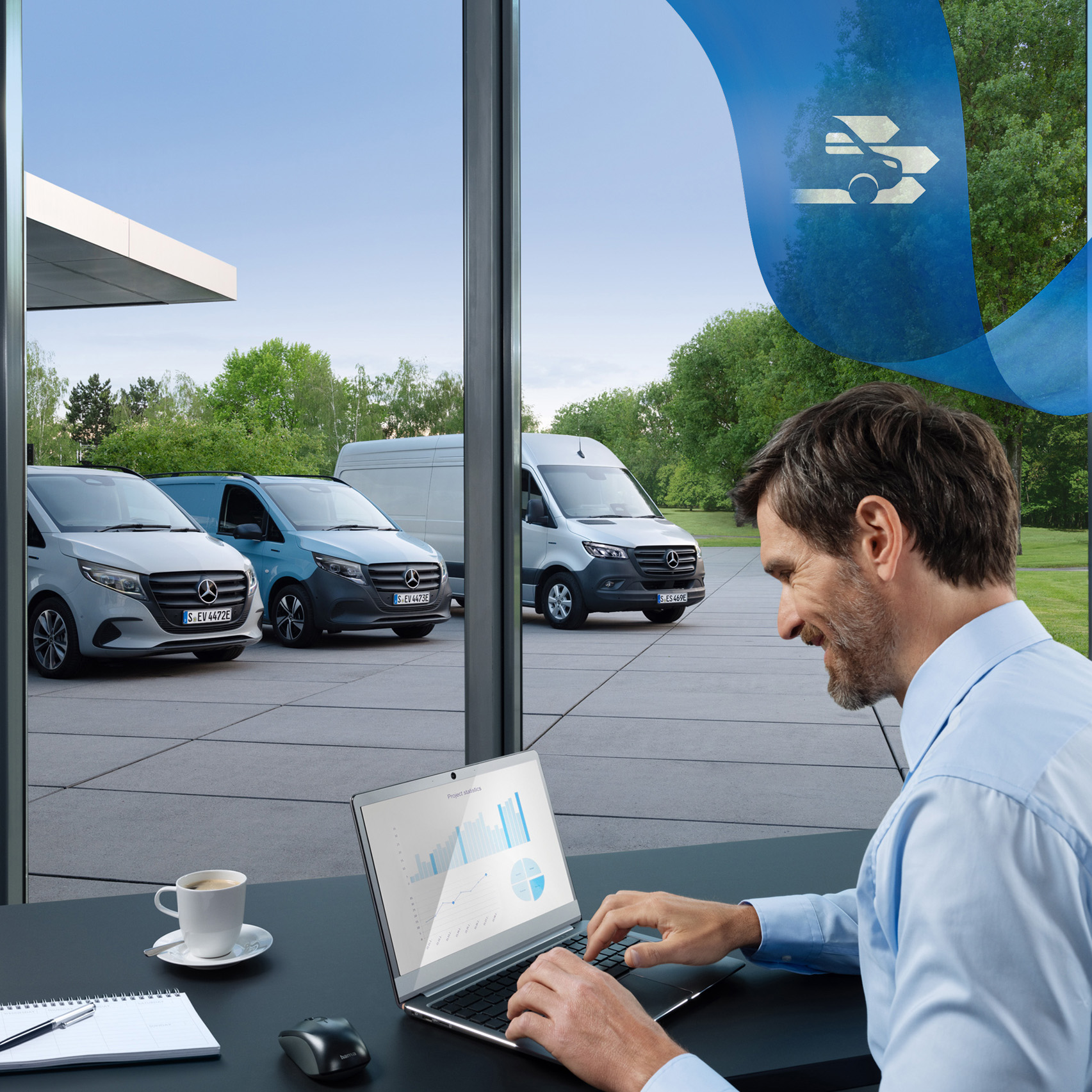 ServiceCare til varebiler | Mercedes-Benz varebiler Mand bruger computer på kontor med Mercedes-Benz varebiler i baggrunden.