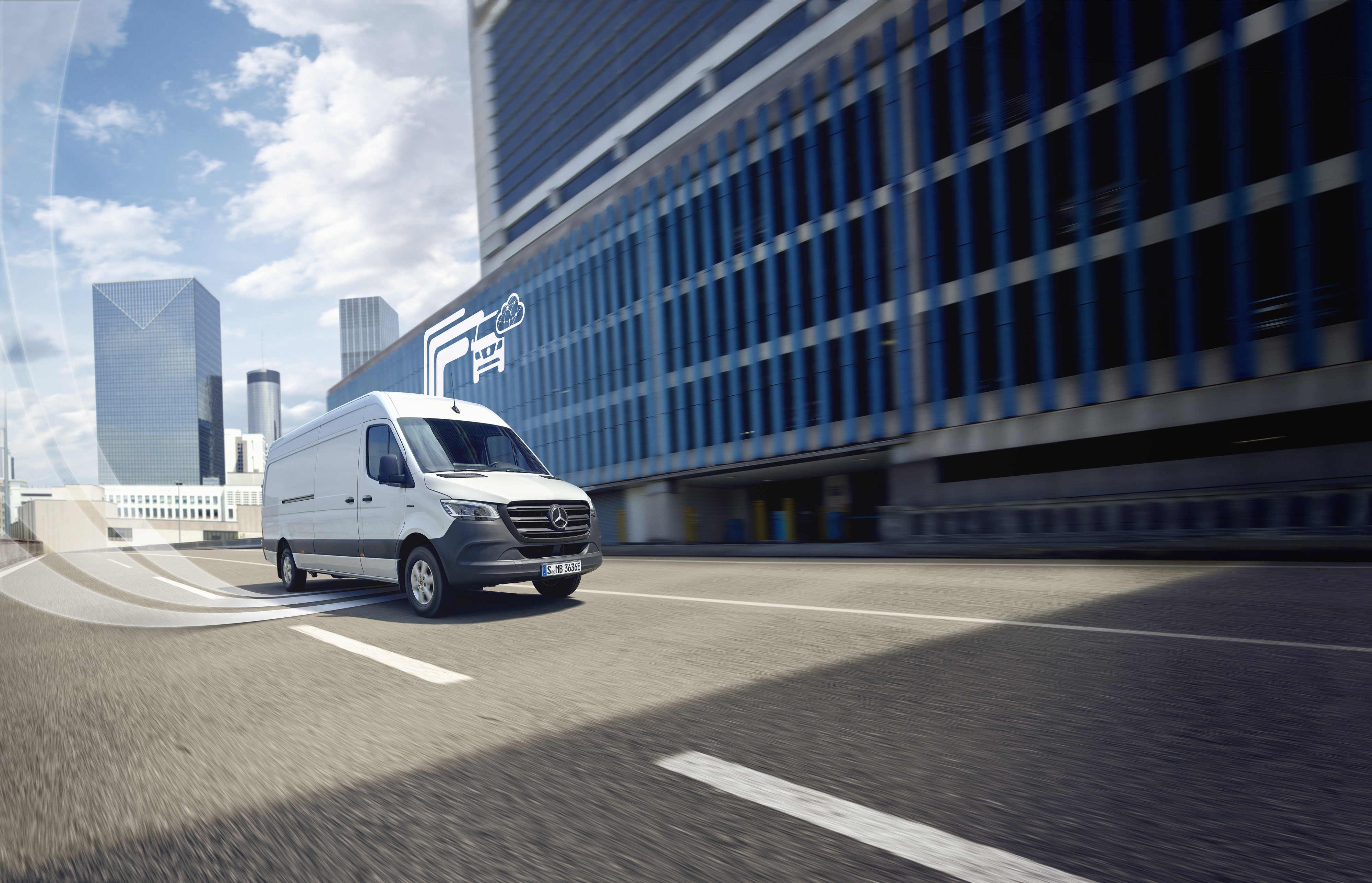 Mercedes-Benz | Varebilsteknologi | Digitale tjenester Hvid Mercedes-Benz varebil kører gennem byen, digitalt symbol på Mercedes-Benz teknologi i baggrunden.