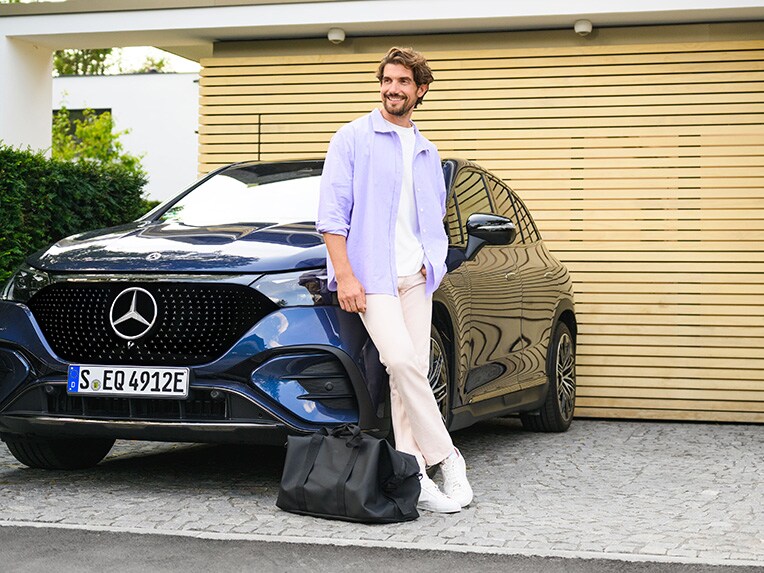 En mand, der læner sig mod et Mercedes-Benz bil og kigger op på himlen. 