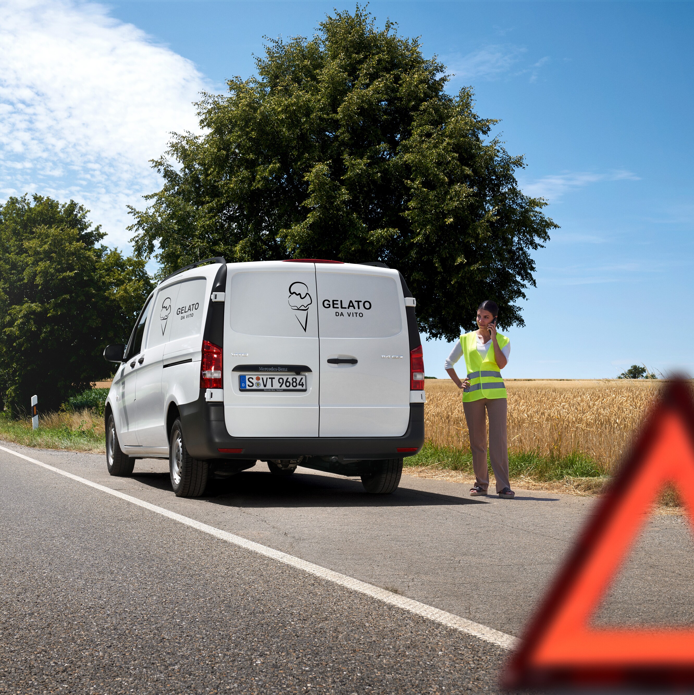 Kvinde står i vejkanten og ringer efter Mercedes-Benz vejhjælp.