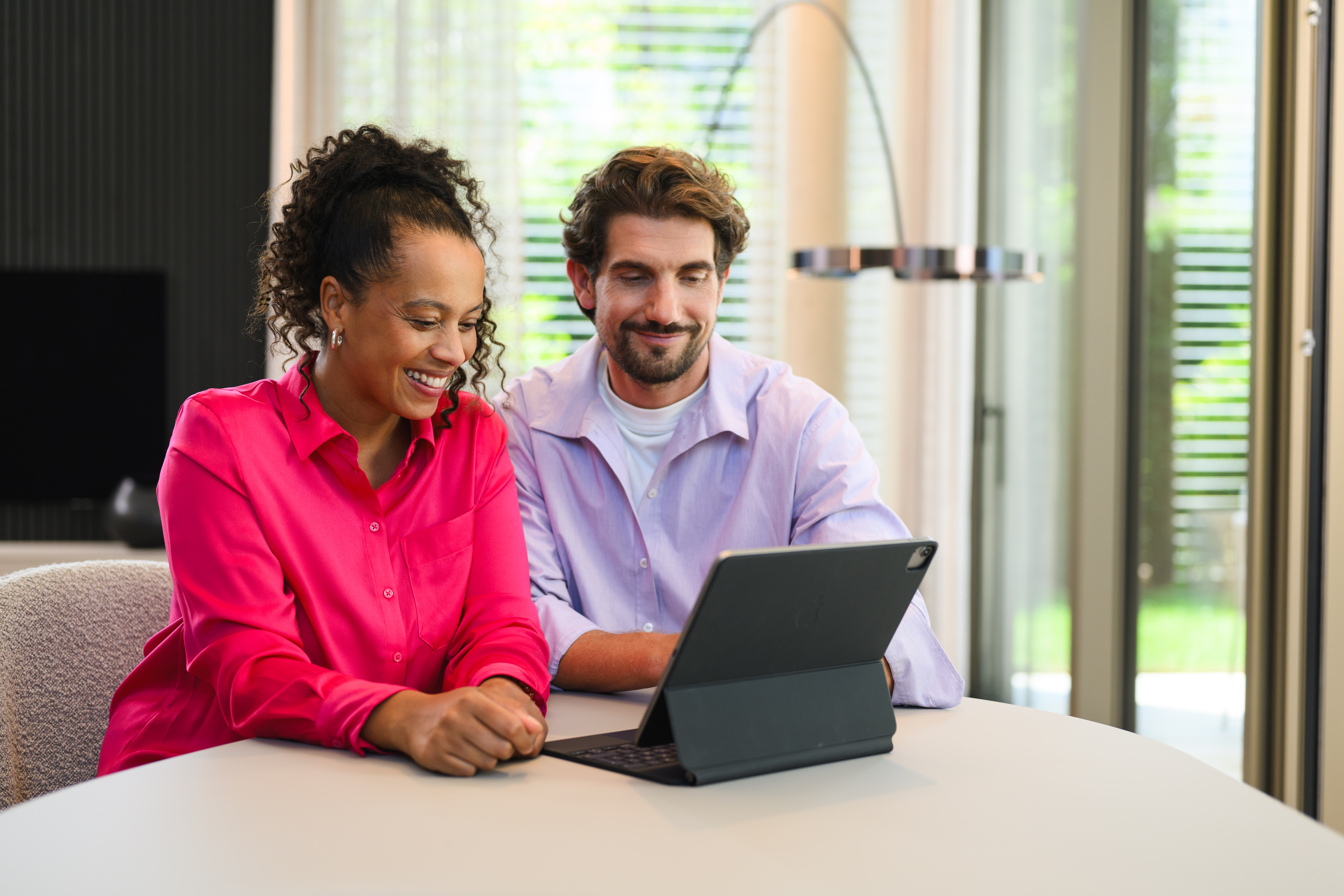 Online Showroom | Aktuelle kampagner | Mercedes-Benz Mand og kvinde sidder med en tablet og køber en Mercedes-Benz online