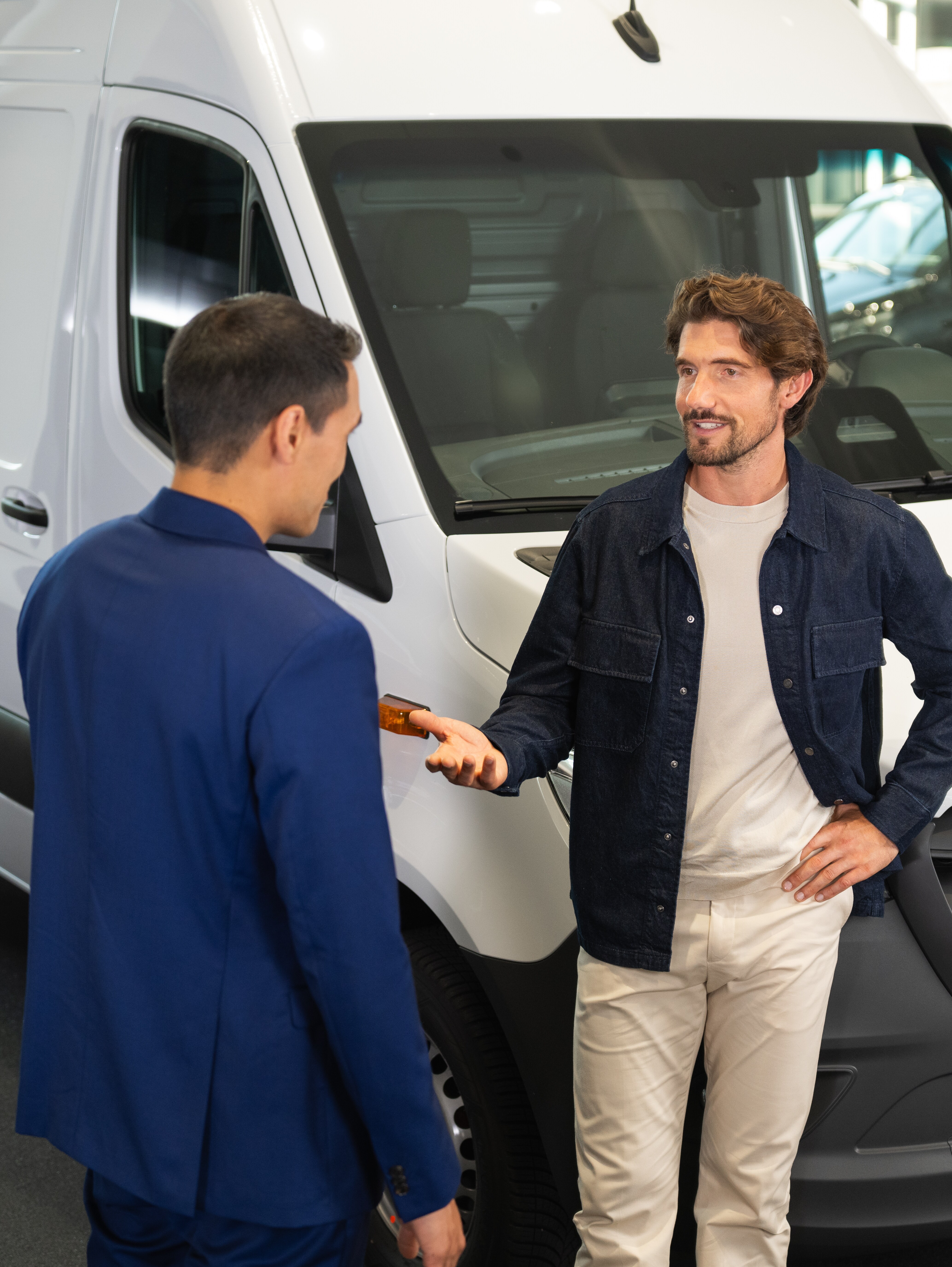 Mercedes-Benz kunderådgiver i samtale med kunde foran hvid Sprinter Kassevogn